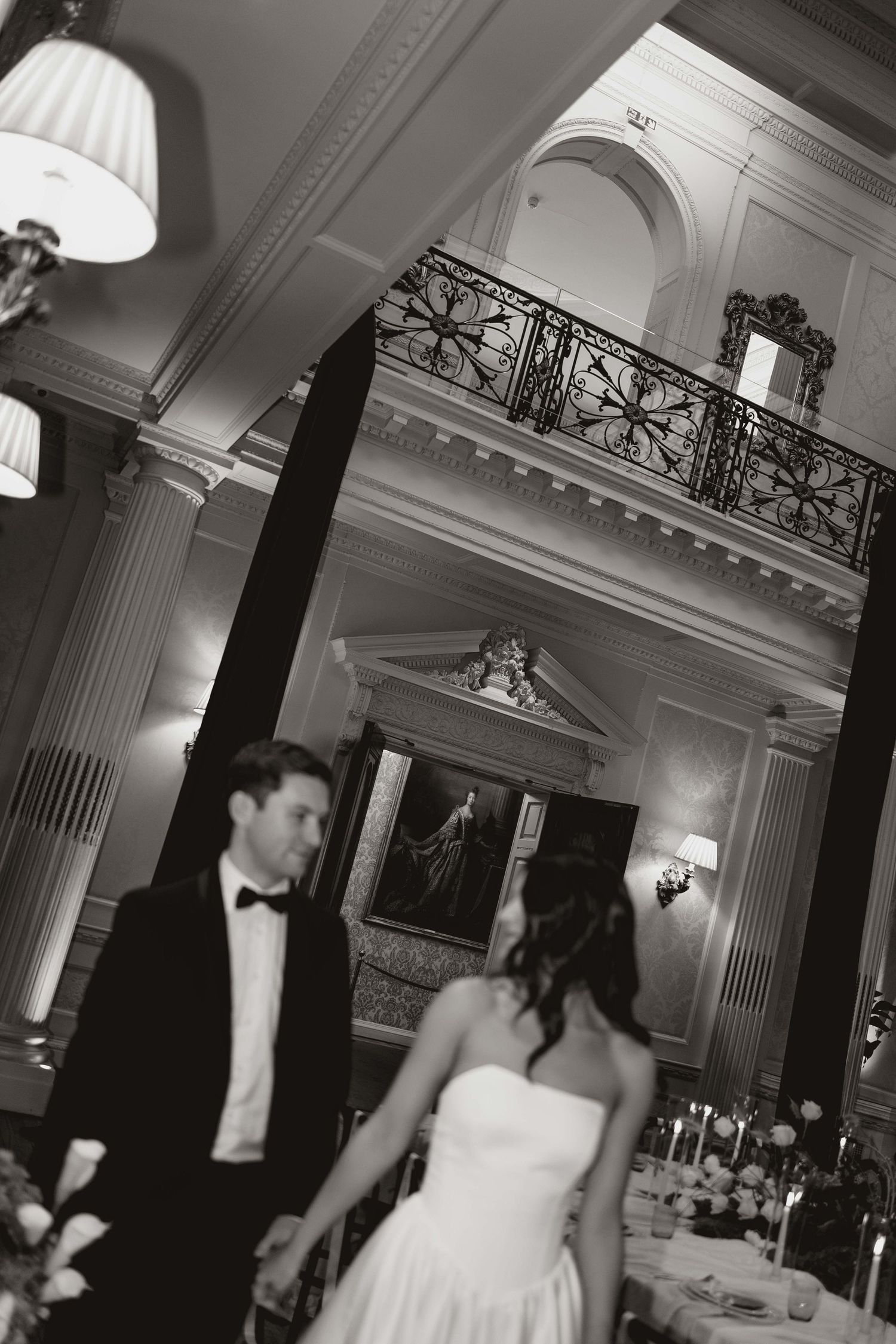 Black and white wedding reception photos showing elegant ballroom interior with columns and ornate balcony railings.