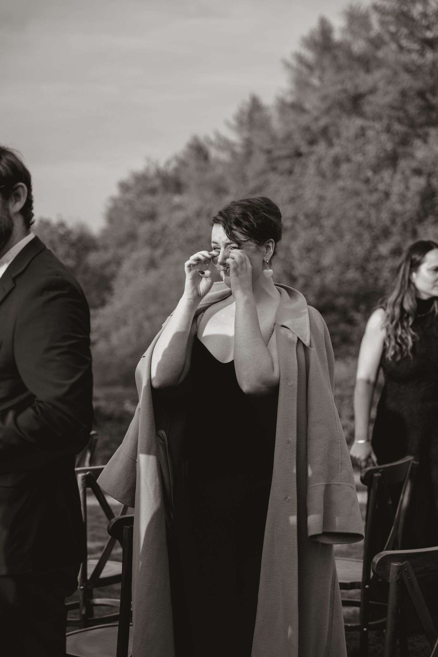 A black and white sequence of a couple kissing at a wedding ceremony with trees in the background.
