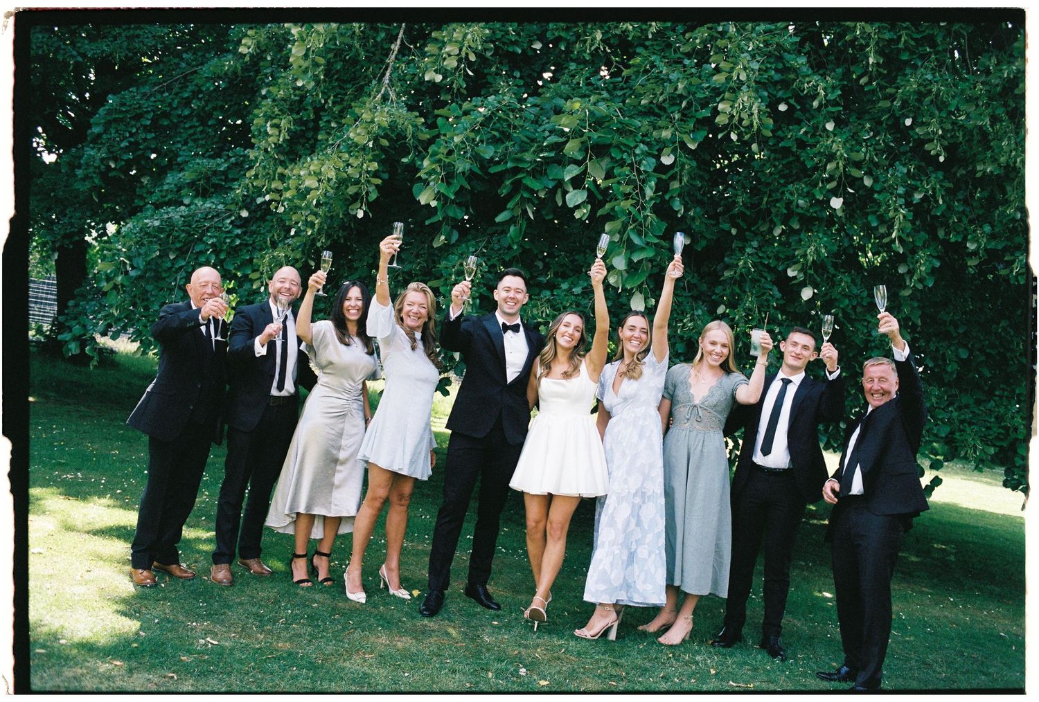 A panoramic collage of wedding guests celebrating outdoors in a lush green garden setting.
