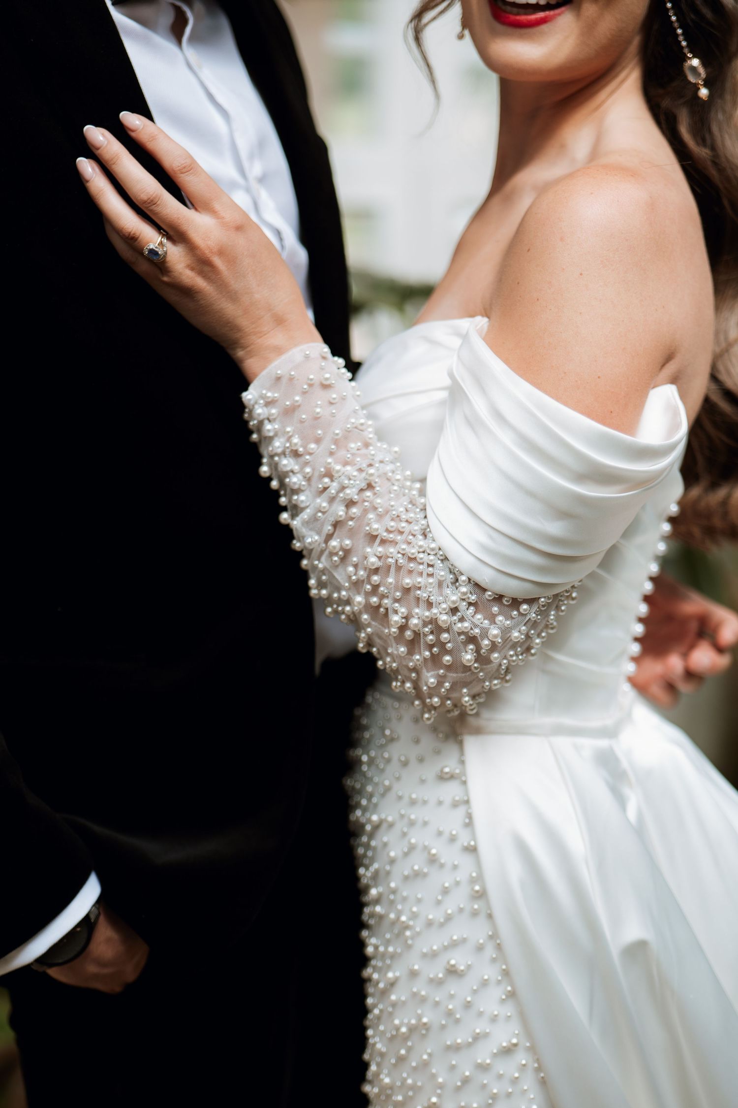 A white wedding dress sleeve adorned with delicate pearl beading details creates an elegant bridal look.