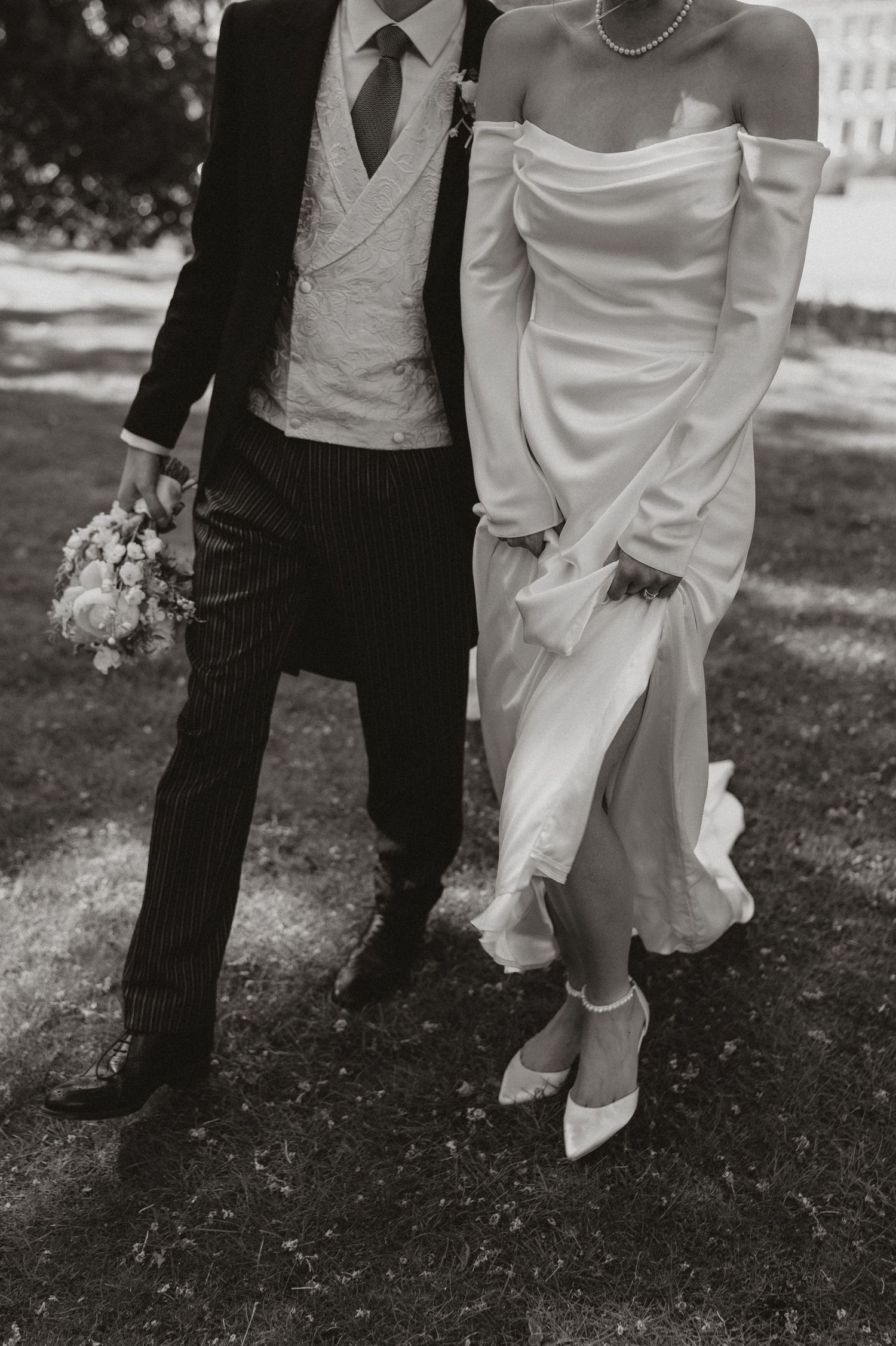Black and white photo series showing close-up details of a bride's white dress and groom's formal attire during outdoor wedding.