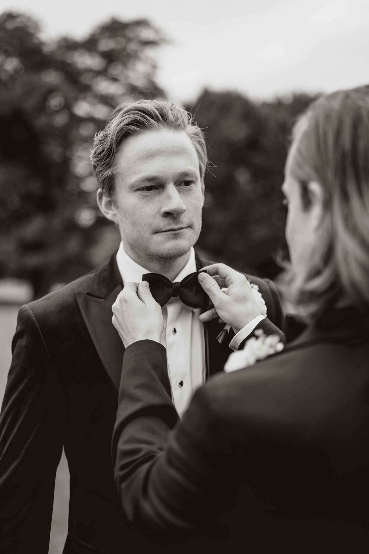 Black and white photo sequence showing a groom getting his bowtie adjusted during wedding preparations.