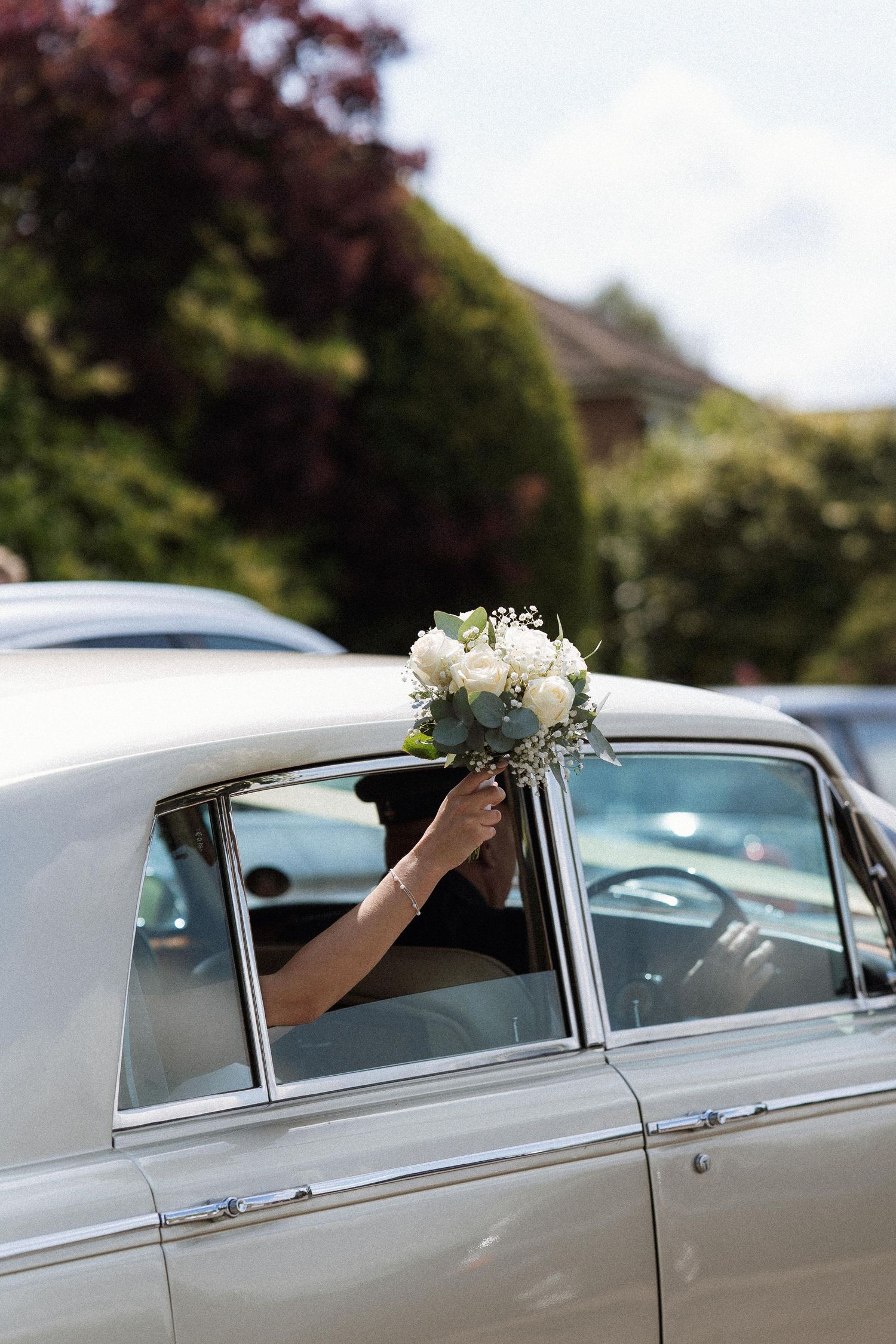 A sequence of photos showing a white vintage wedding car with floral decorations on its roof.
