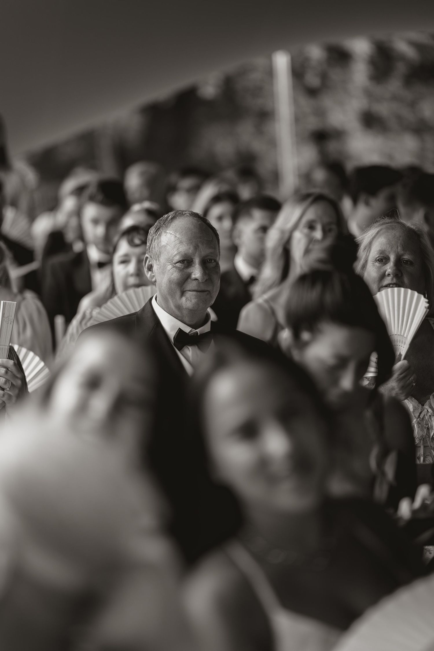 A black and white crowd shot showing people sitting in an audience with soft focus and shallow depth of field.