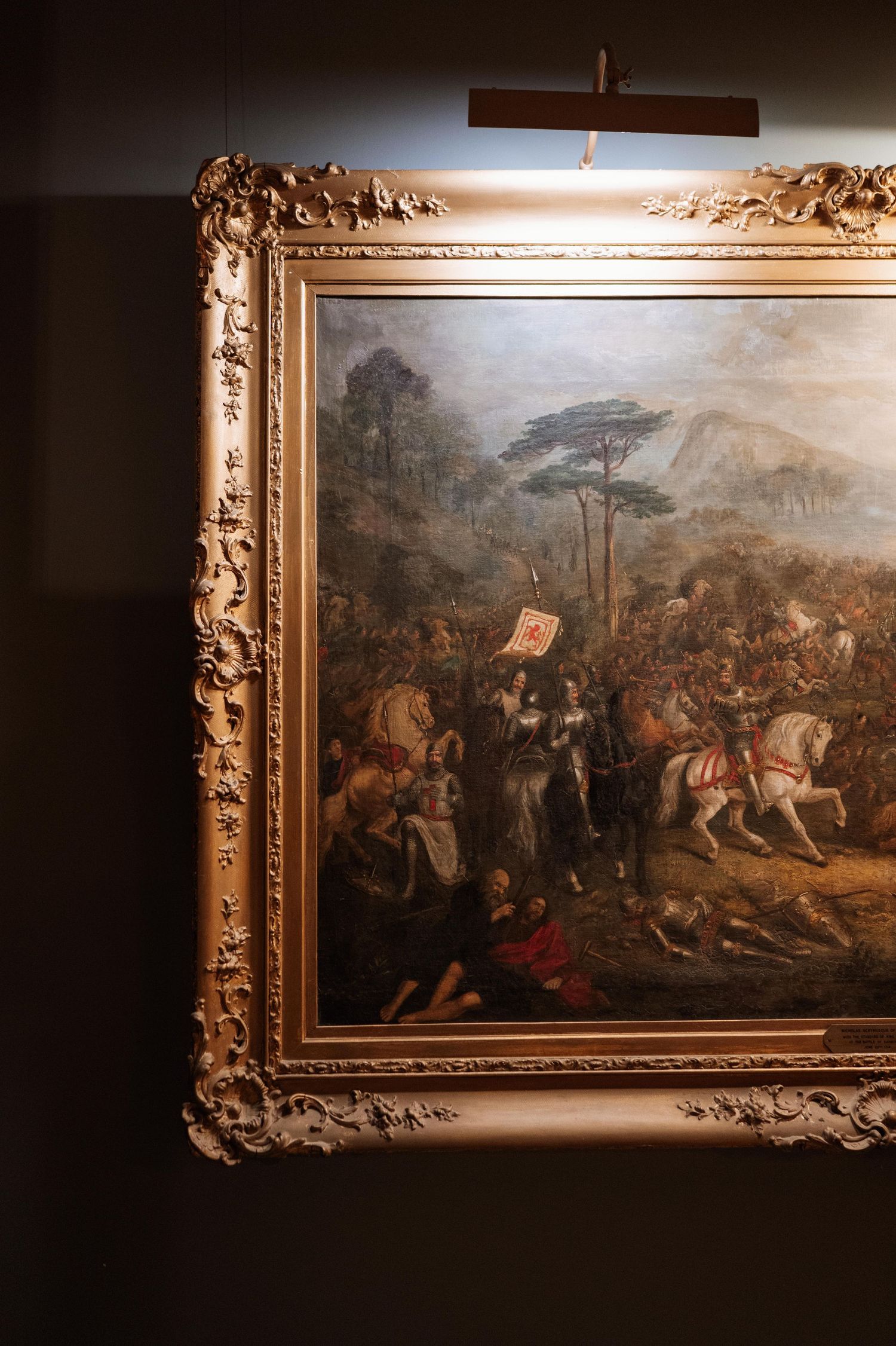 Series of ornate gold-framed classical battle paintings displayed on a dark gallery wall.