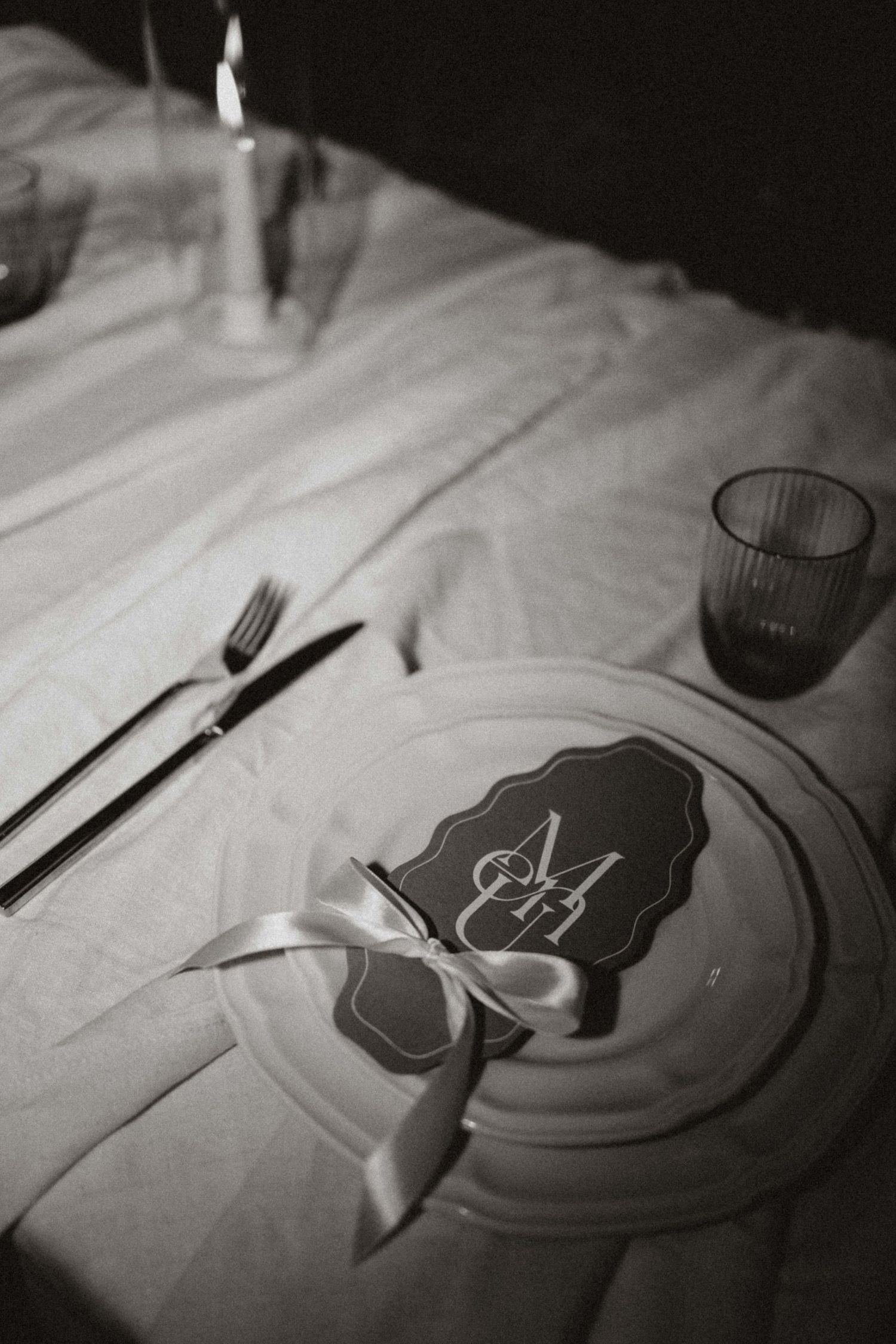 Black and white photo series showing elegant table settings with plates, cutlery and glassware in dramatic lighting.