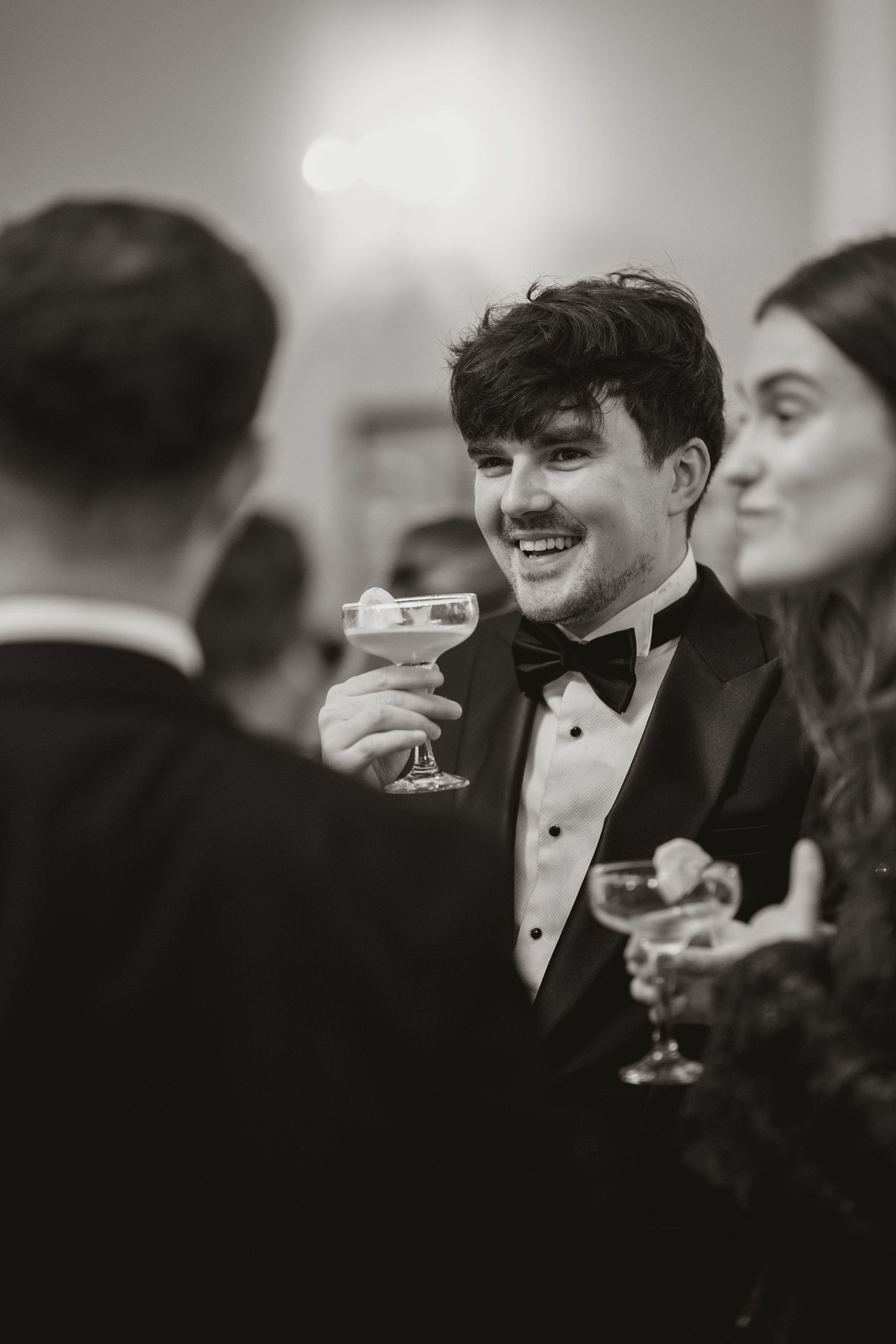 A series of black and white photos showing people in formal attire enjoying drinks at an elegant party.