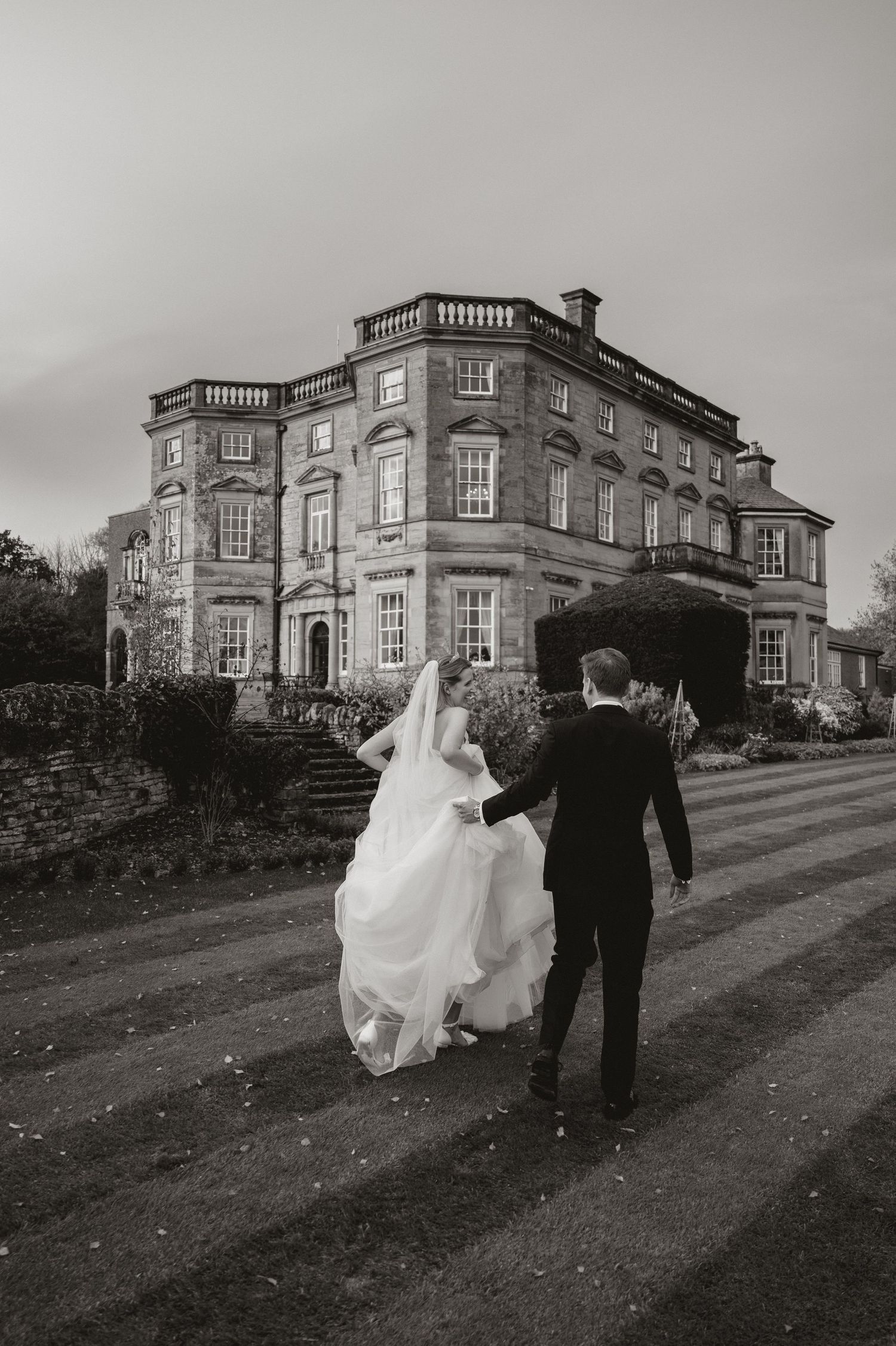 A black and white photo sequence shows a couple walking up a hill towards an elegant historic mansion estate.