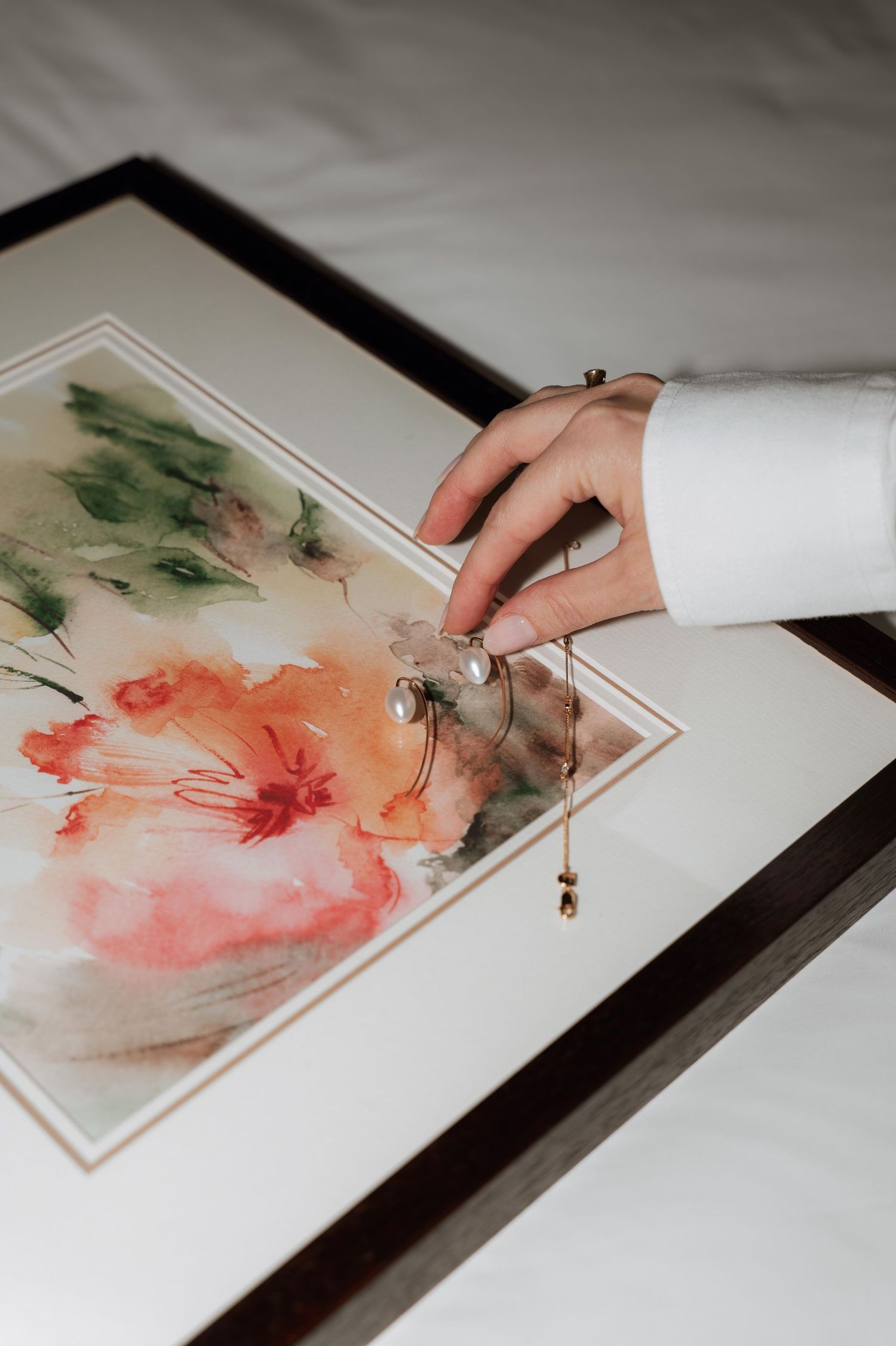Artist's hand creating delicate watercolor painting with pink and green tones on white paper in progressive sequence.