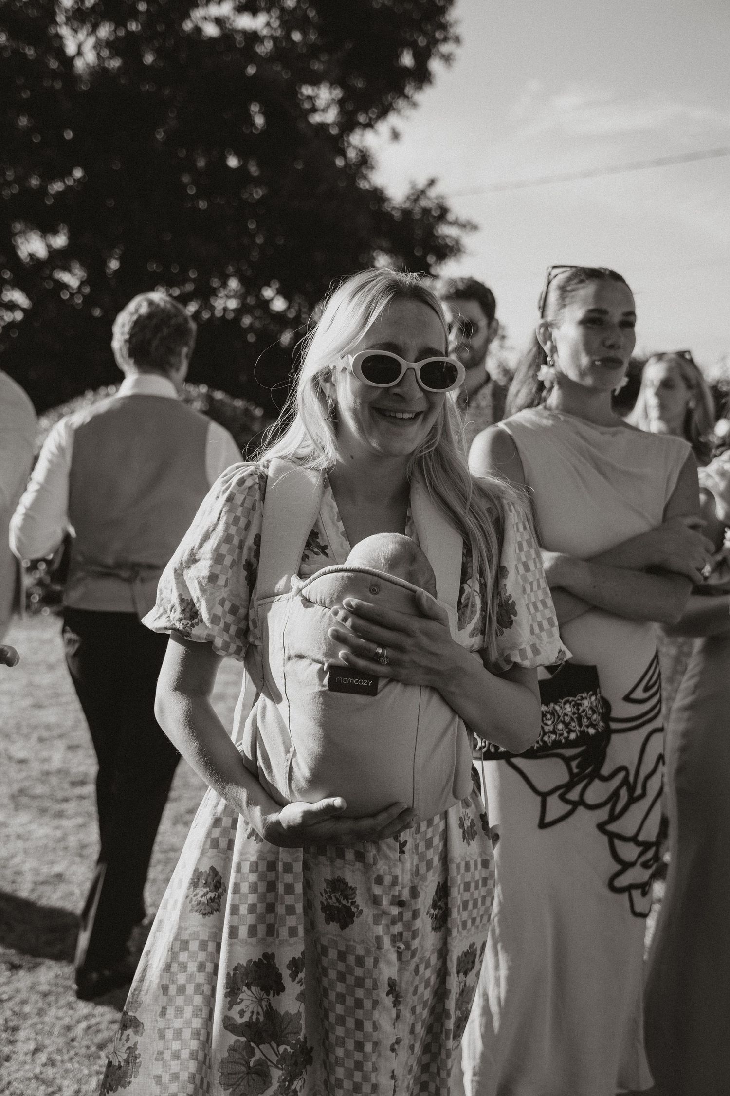 A series of black and white candid photos showing people embracing and laughing together at an outdoor gathering.
