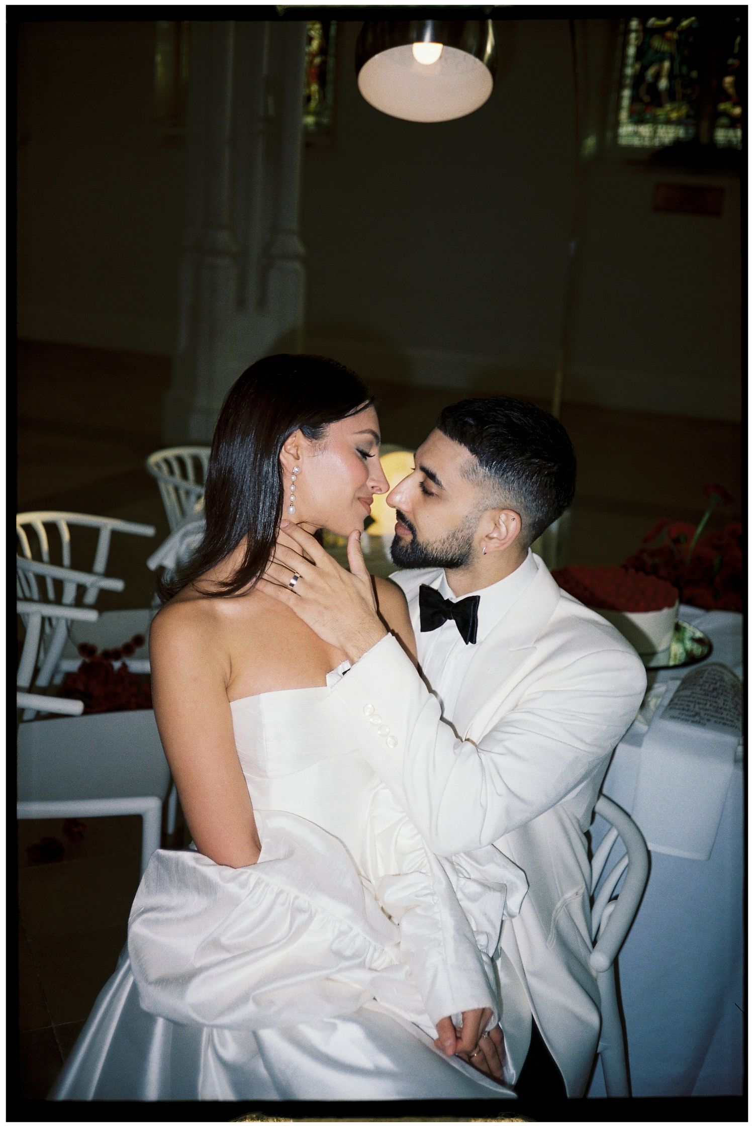 A couple in formal attire sharing an intimate moment at a wedding reception.