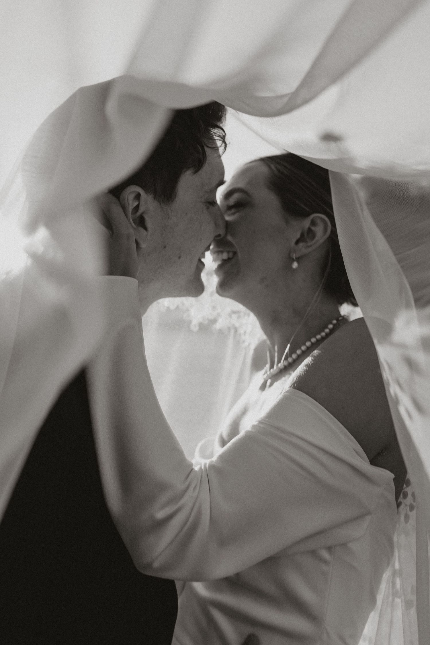 A black and white photo series showing a person wearing a white veil in various artistic poses and lighting.
