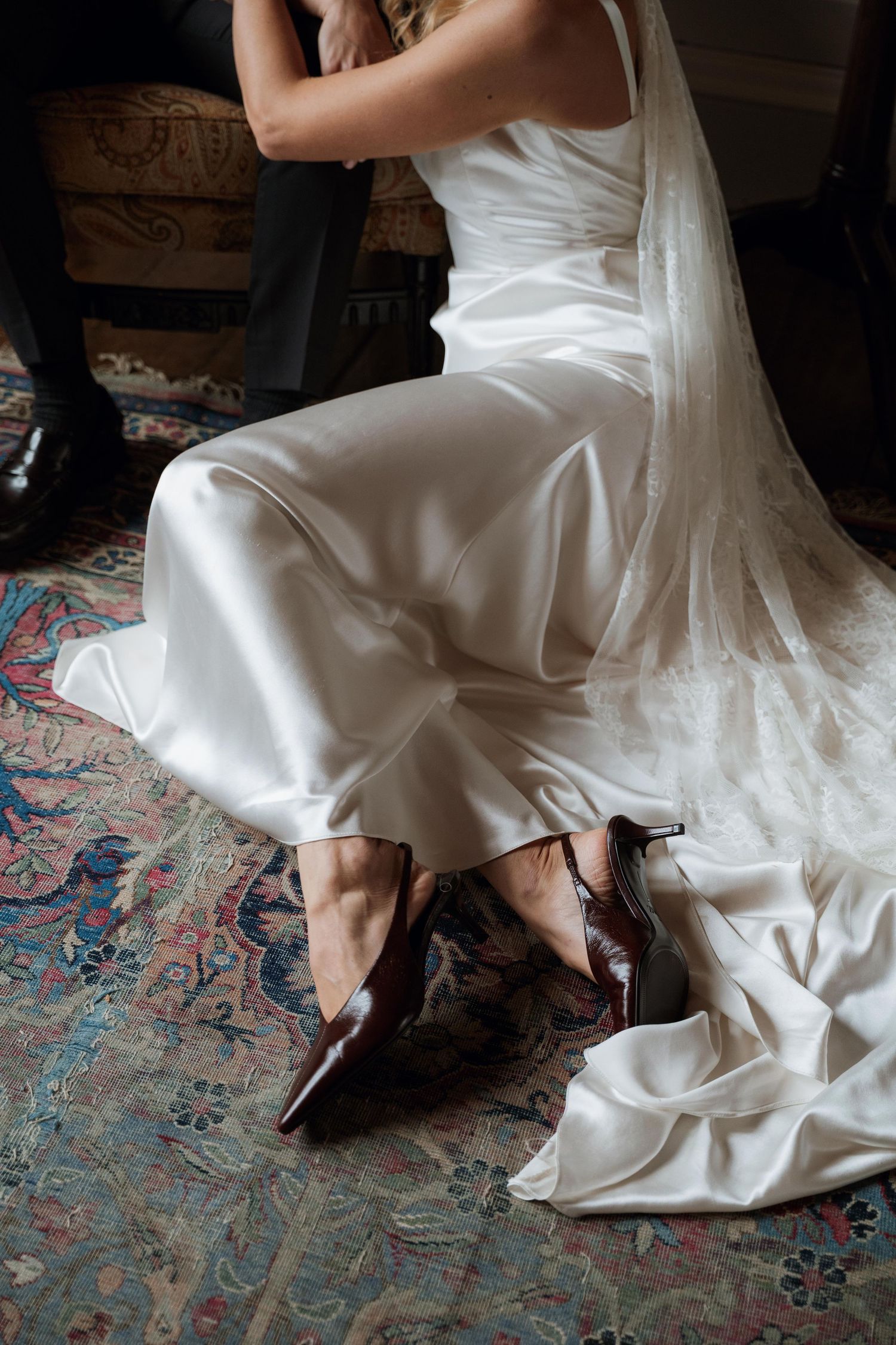 A close-up series of white wedding dress details showing the hem and shoes against an ornate vintage rug.