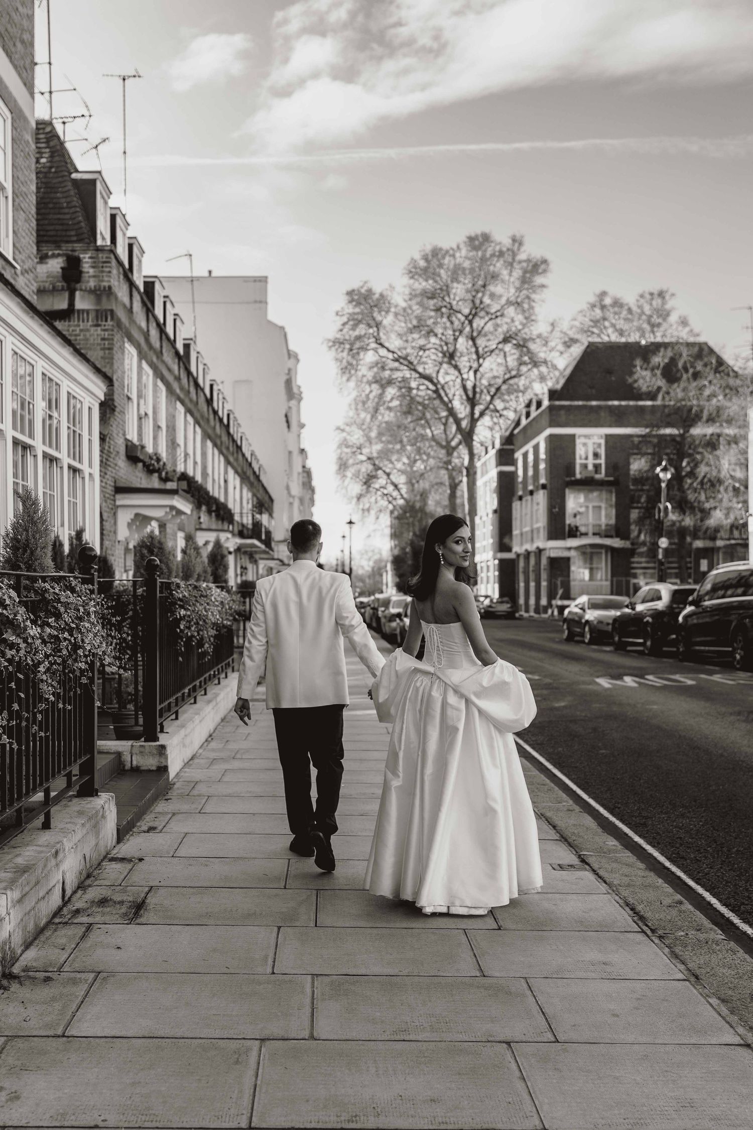 Two people walk together down a sidewalk in a historic neighborhood, shown in a series of black and white photographs.