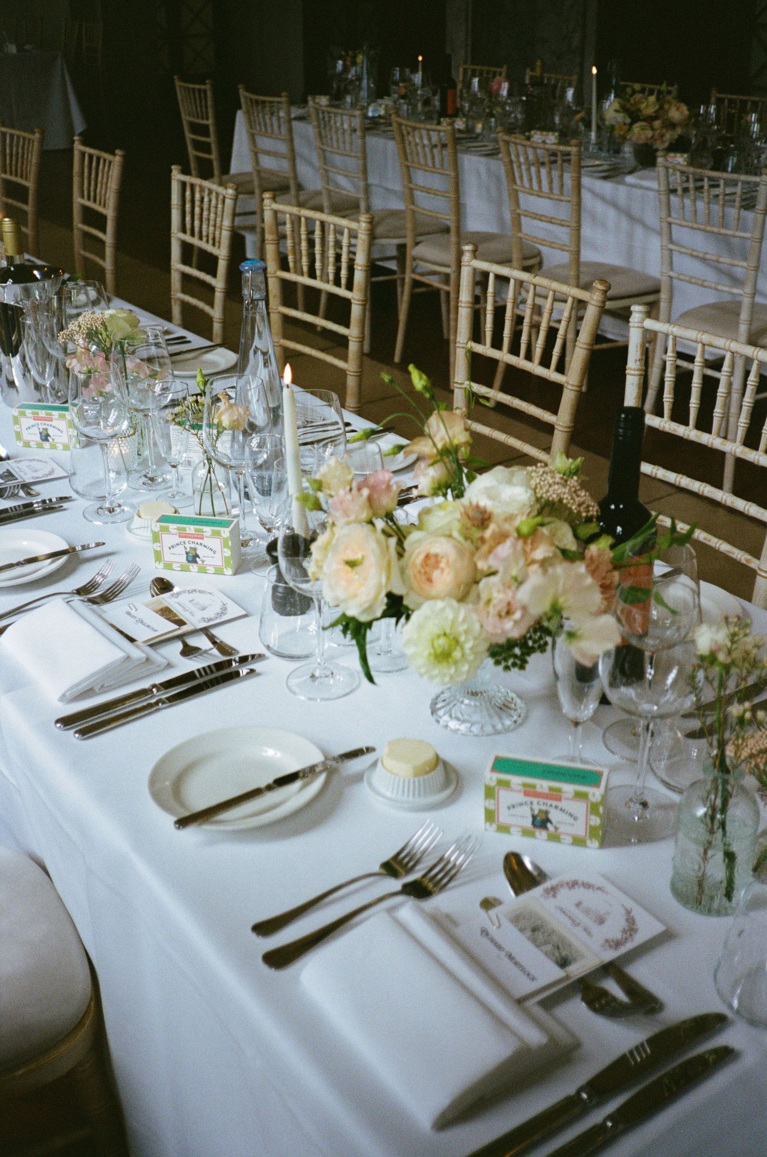 Elegant wedding reception table settings with white linens, chiavari chairs, and soft floral centrepieces.