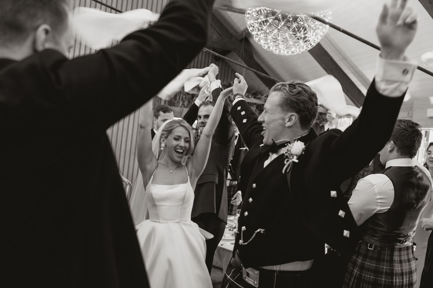 A series of black and white wedding photos showing joyful moments of celebration and dancing at a reception.