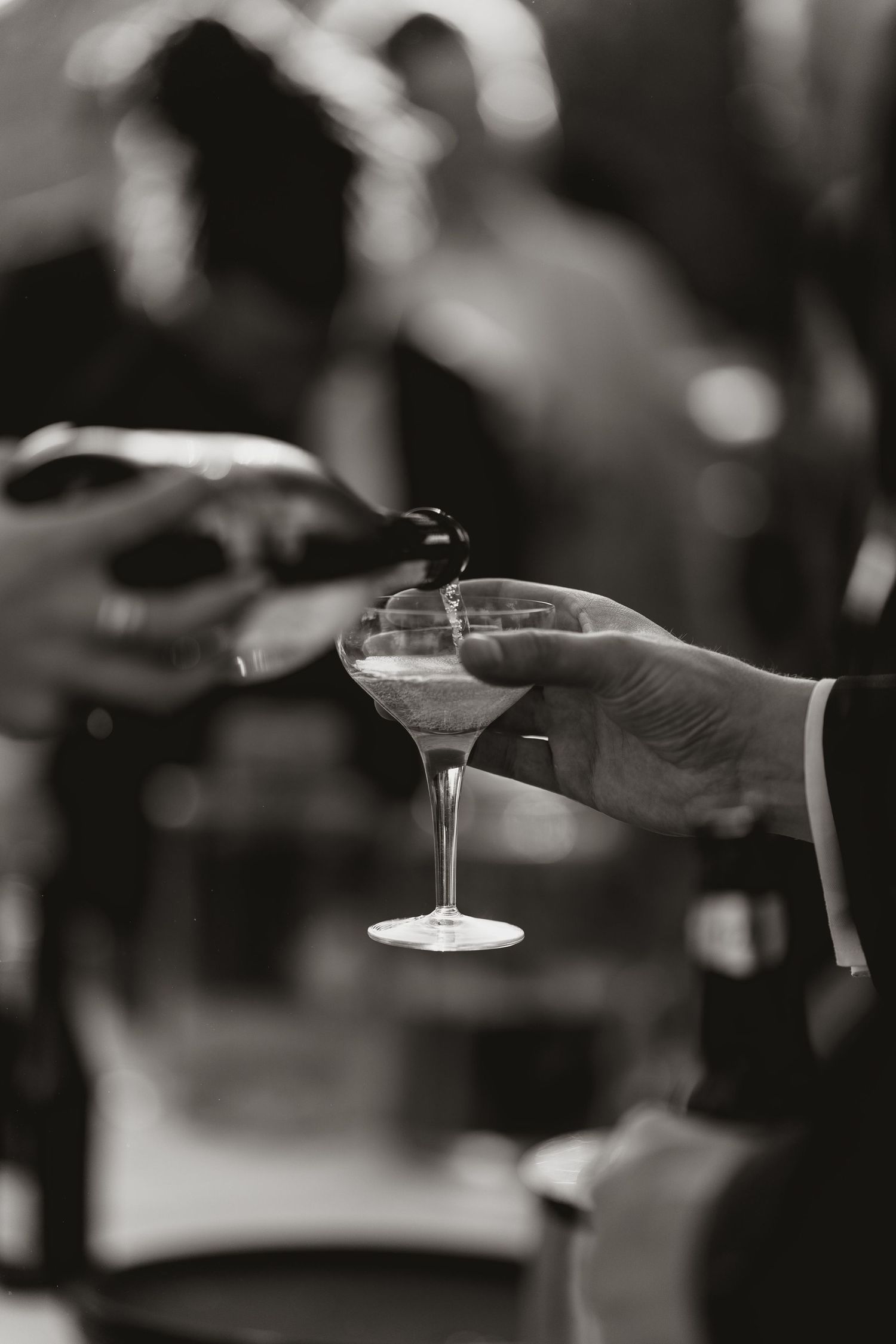 Black and white photo series showing hands holding martini glasses in various positions during a toast.