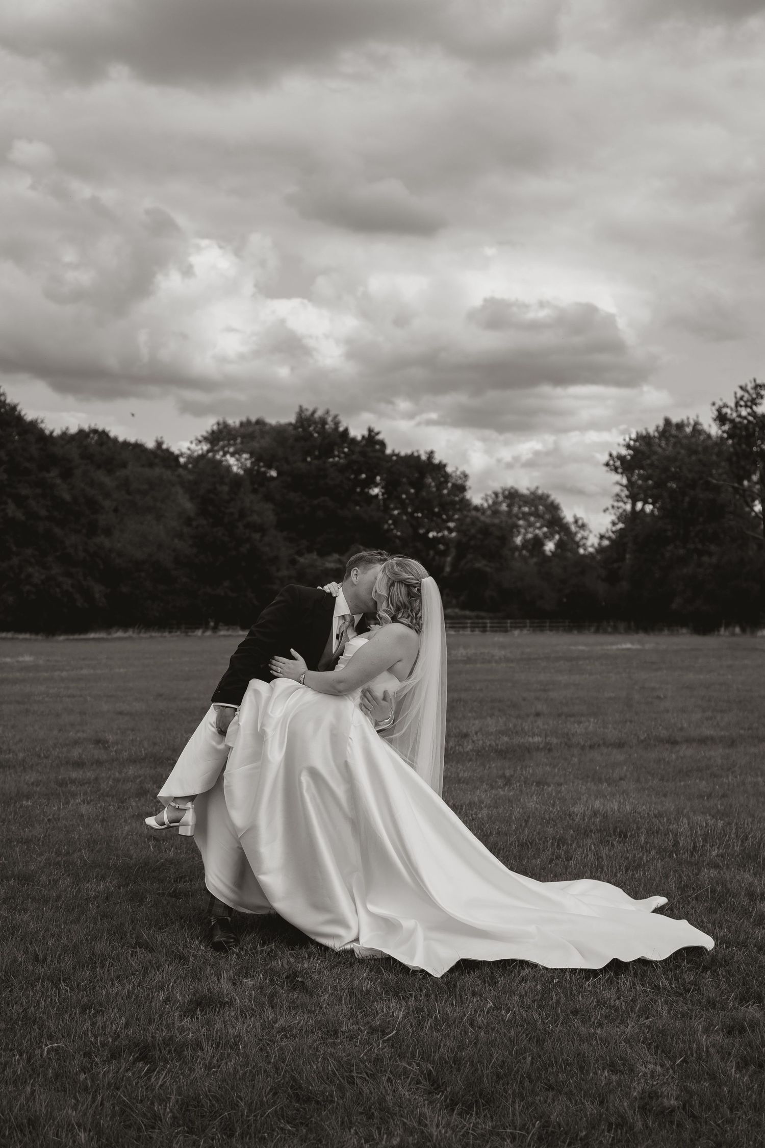 A dramatic black and white photo series shows a figure in a flowing white dress lying in a grassy field under cloudy skies.