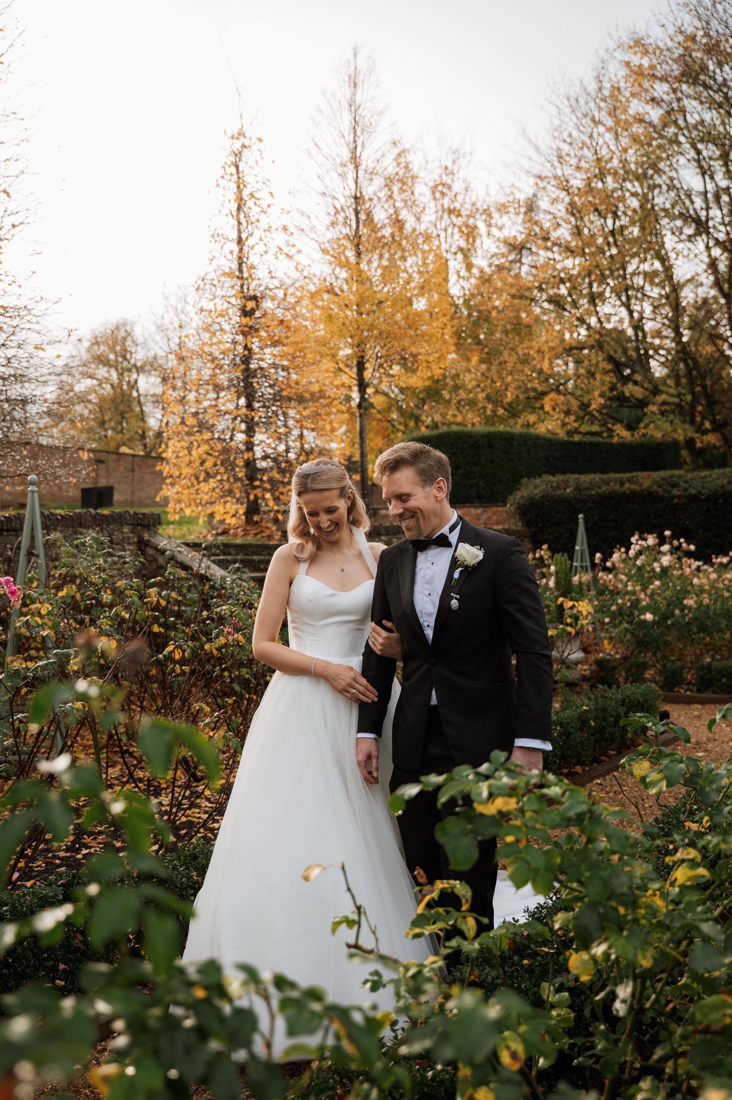 Romantic autumn wedding photoshoot in a garden with blooming roses and fall foliage.