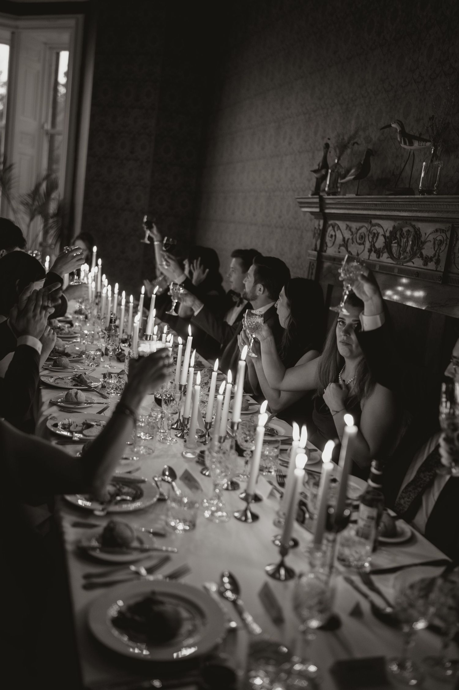 Elegant candlelit dinner table setting with white linens and glassware creates a romantic ambiance at a formal event.