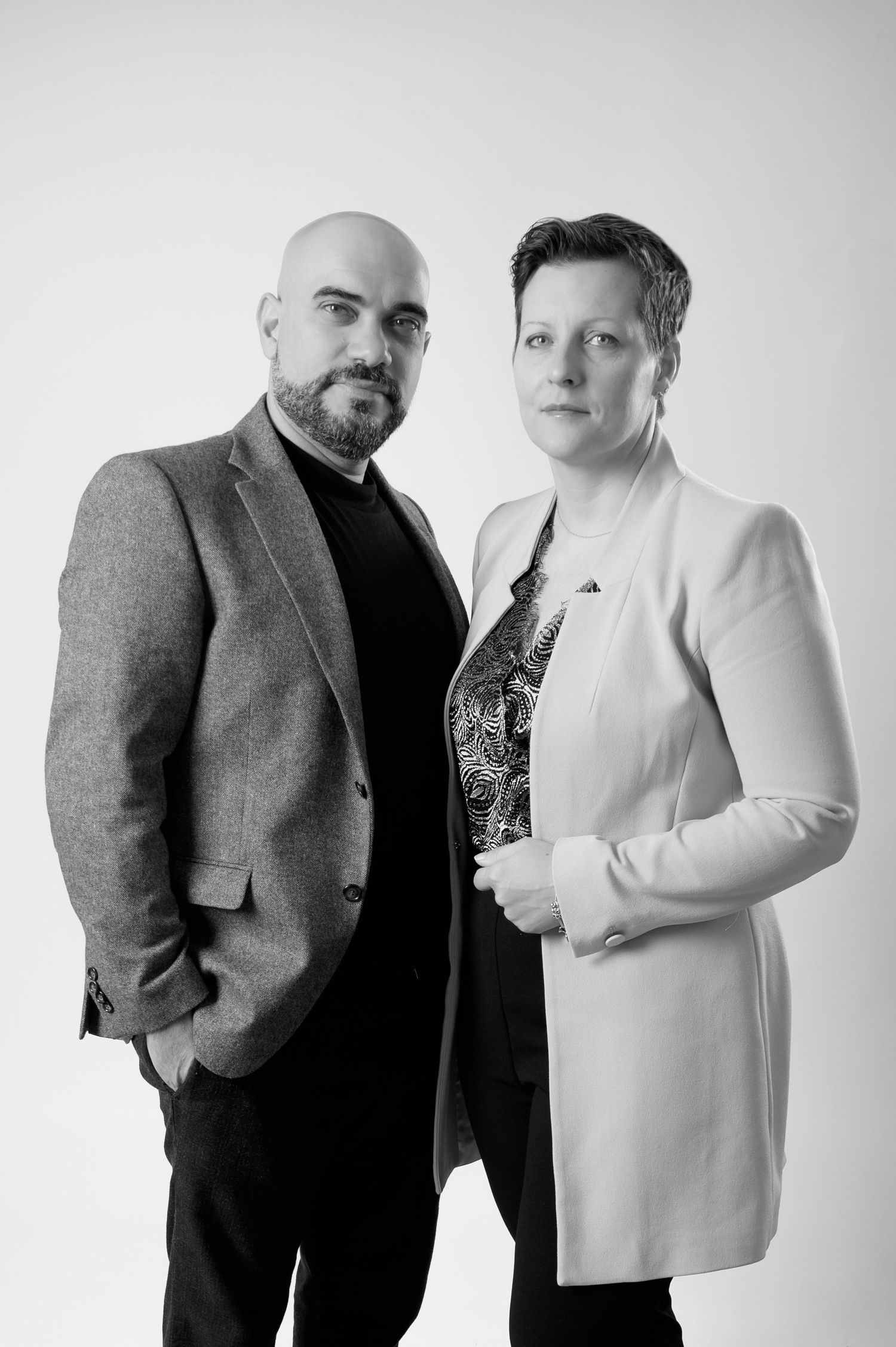 Black and white fashion photo series showing two people in contrasting outfits posing together against white background.