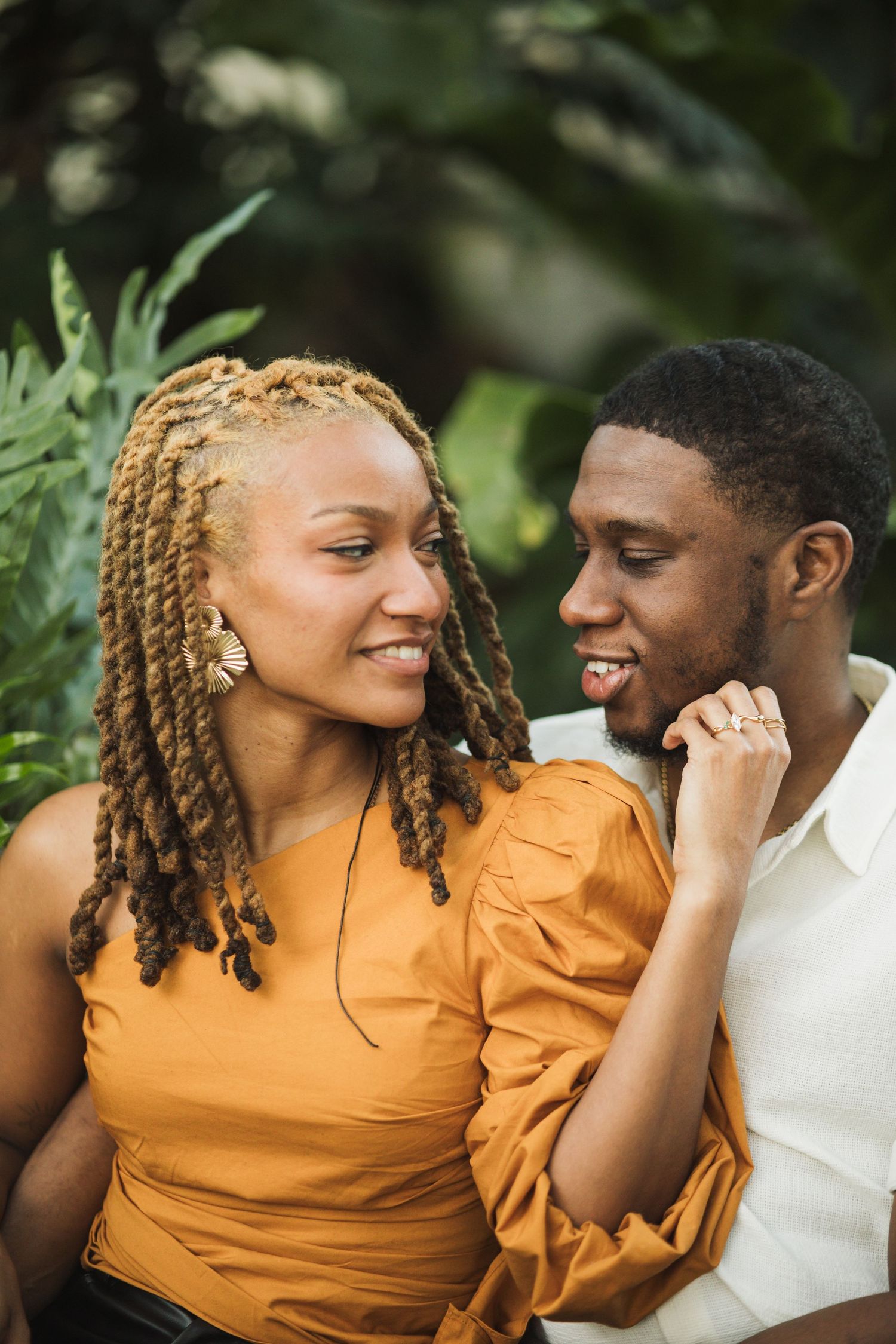 A romantic couple in yellow and white share intimate moments and laughter while embracing in a natural outdoor setting.