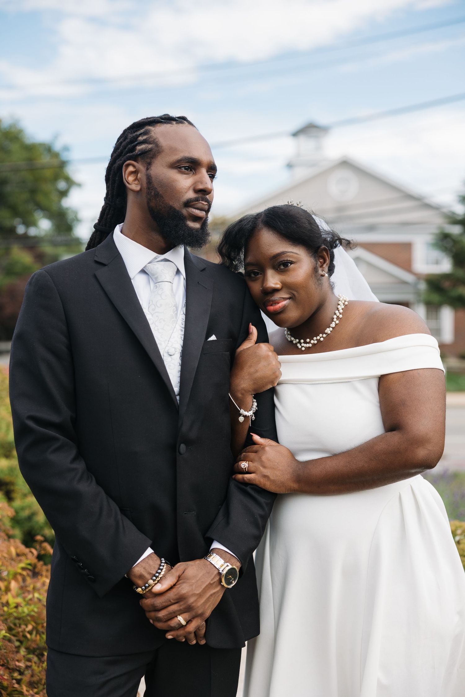 A couple in formal wedding attire share intimate moments in an outdoor garden setting.