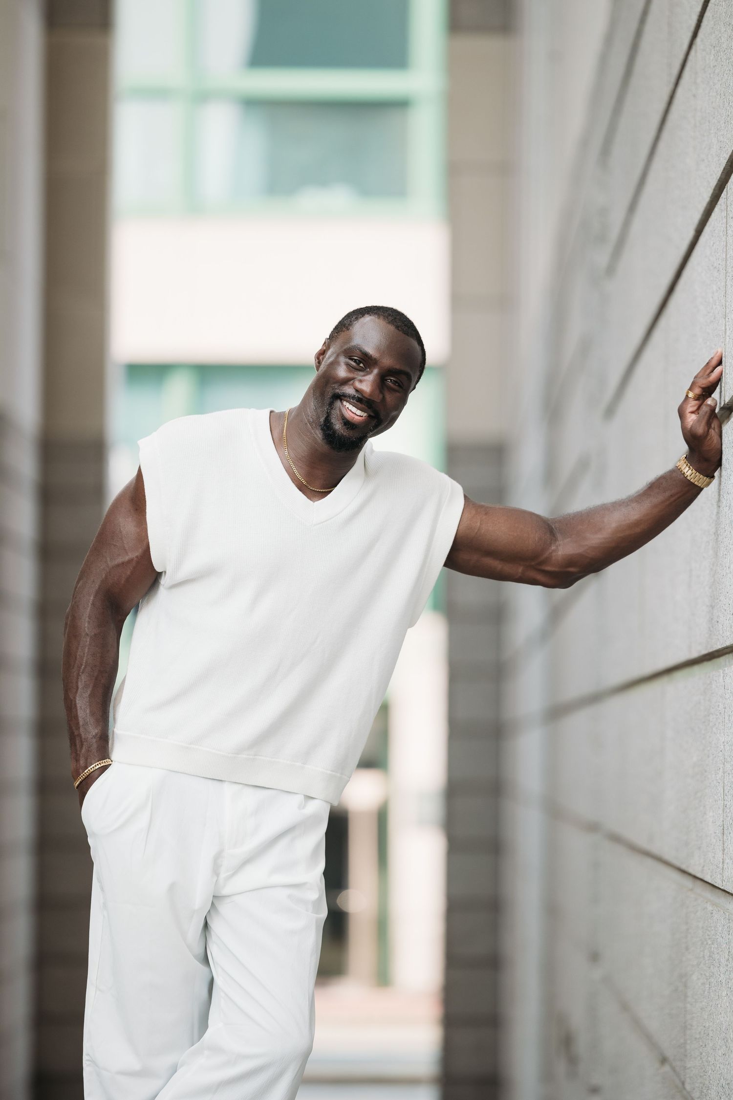 Athletic man in white tank top leaning against concrete wall in dynamic poses showing movement and strength.