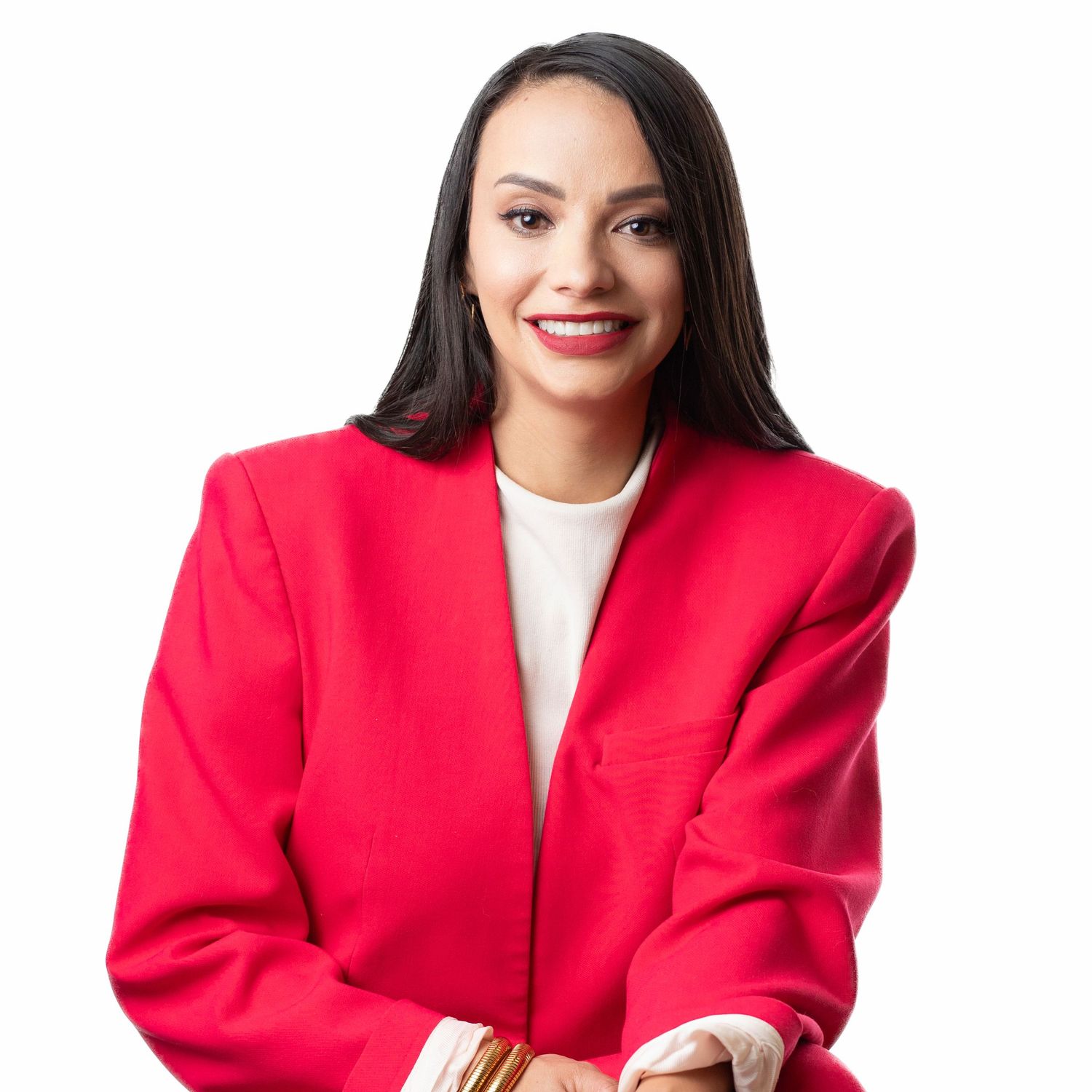 Professional wearing a vibrant red blazer and white top poses with a bright smile against a light background.
