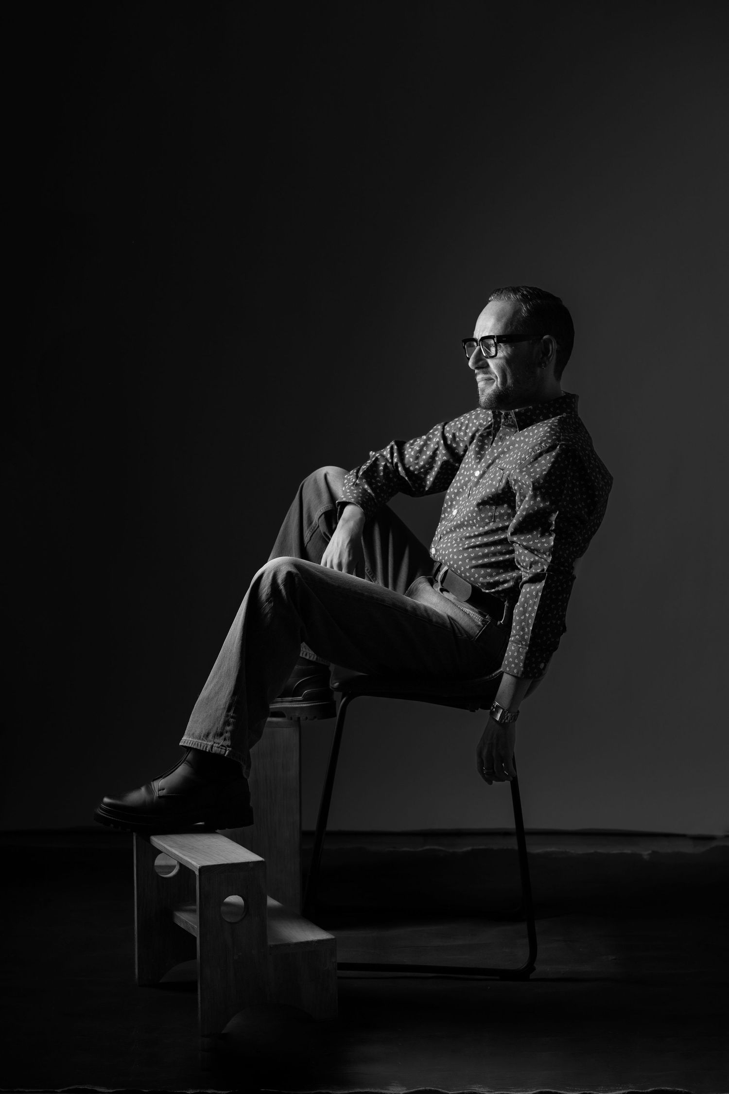 Dramatic black and white series showing a person reclining in a chair against dark background in different poses.