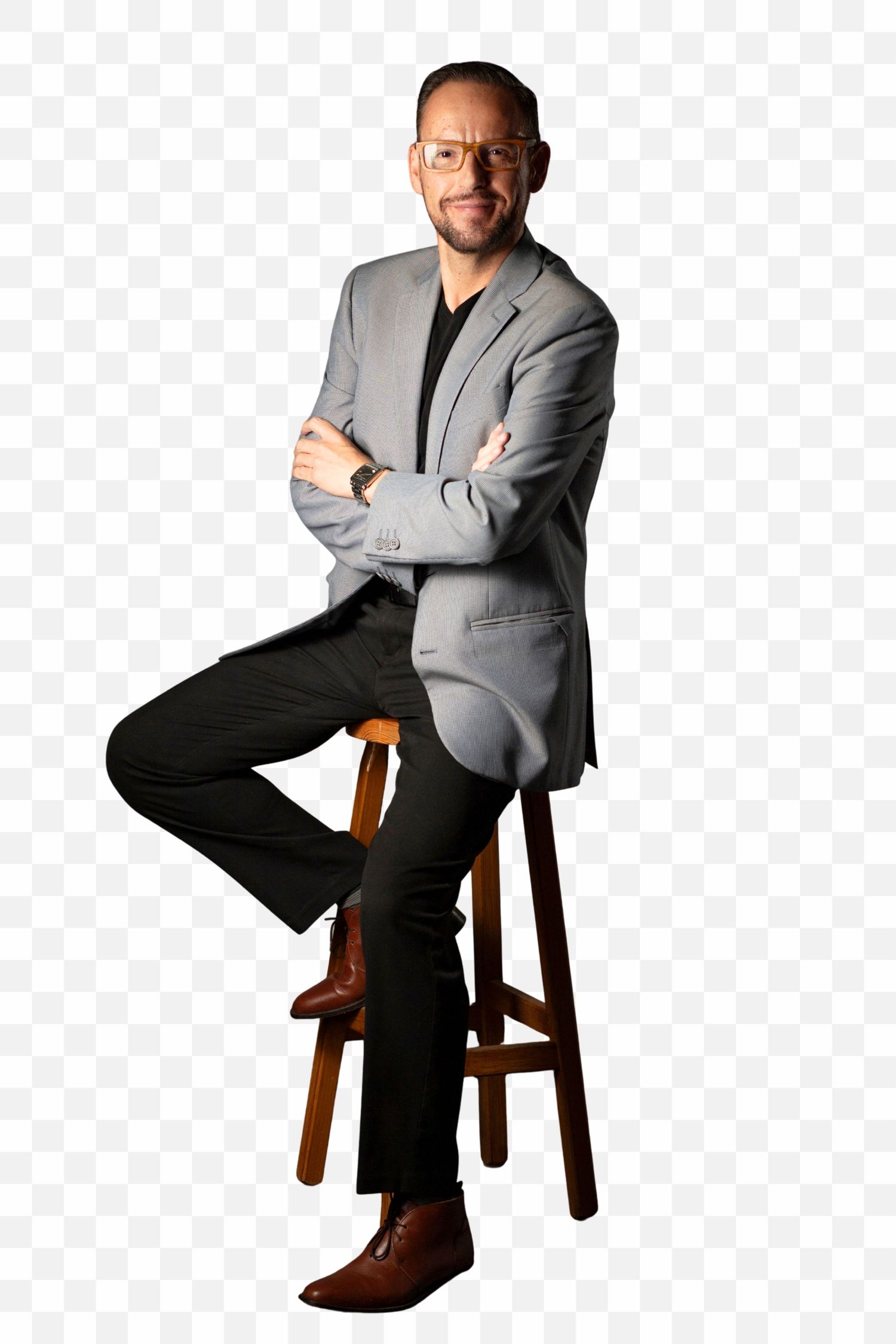 A person in a gray blazer and dark pants sits casually on a wooden stool in three similar poses.