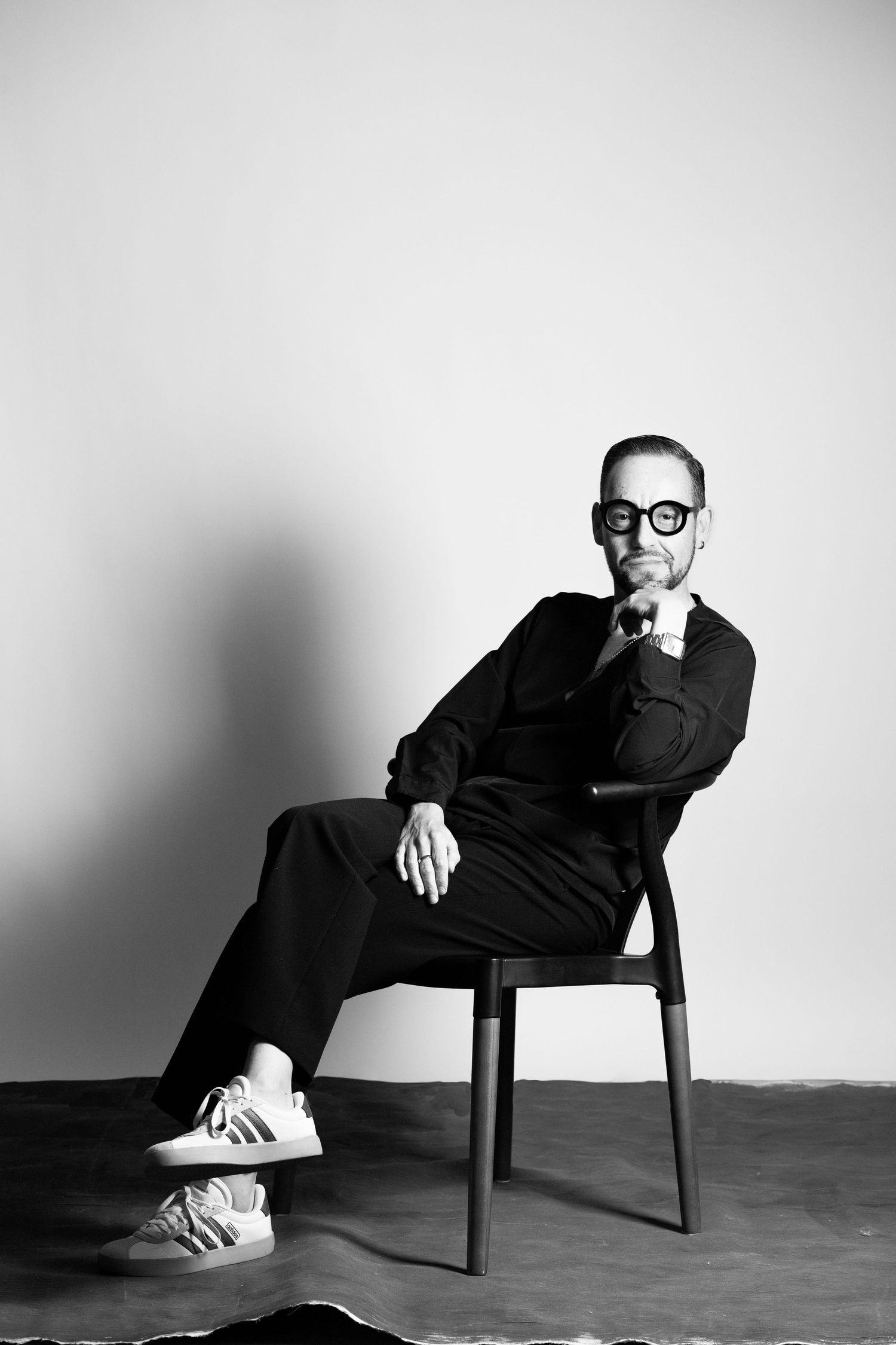 A black and white photo series showing a person in dark clothing sitting in different relaxed poses on a chair.