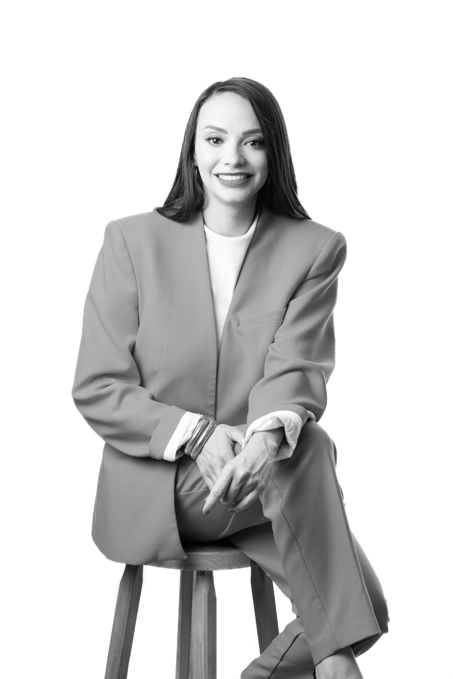 Professional portrait series showing person in gray blazer sitting on chair in various elegant poses against white backdrop.