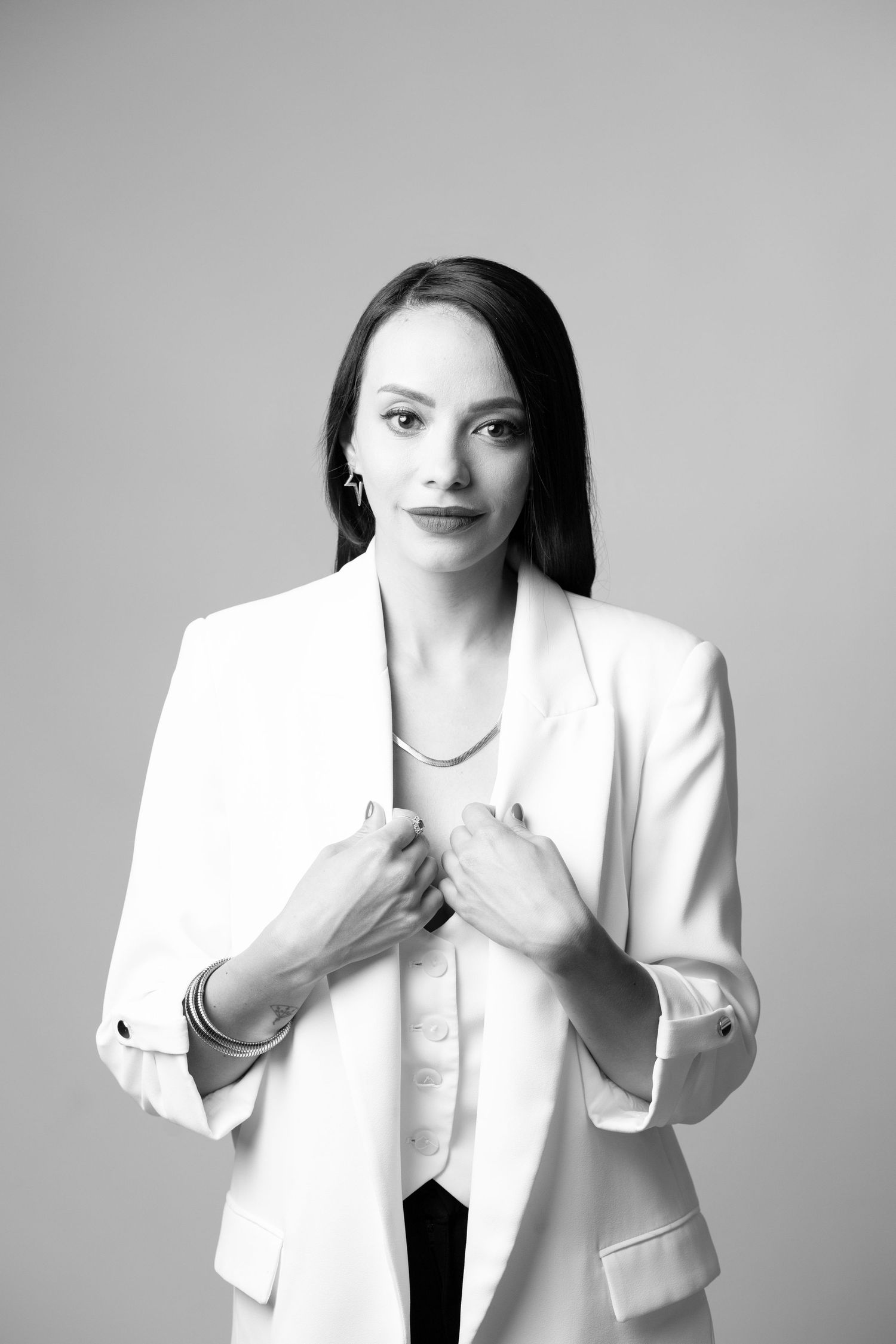 A series of black and white fashion photos showing someone in a white blazer making expressive hand gestures.