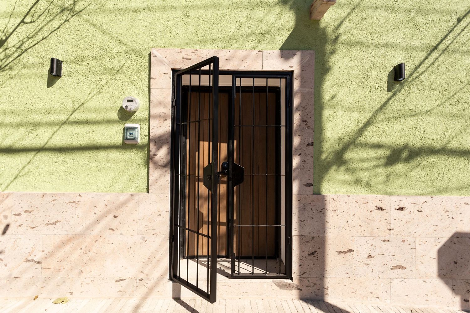 A row of black metal security bars installed on windows against a light colored exterior wall.