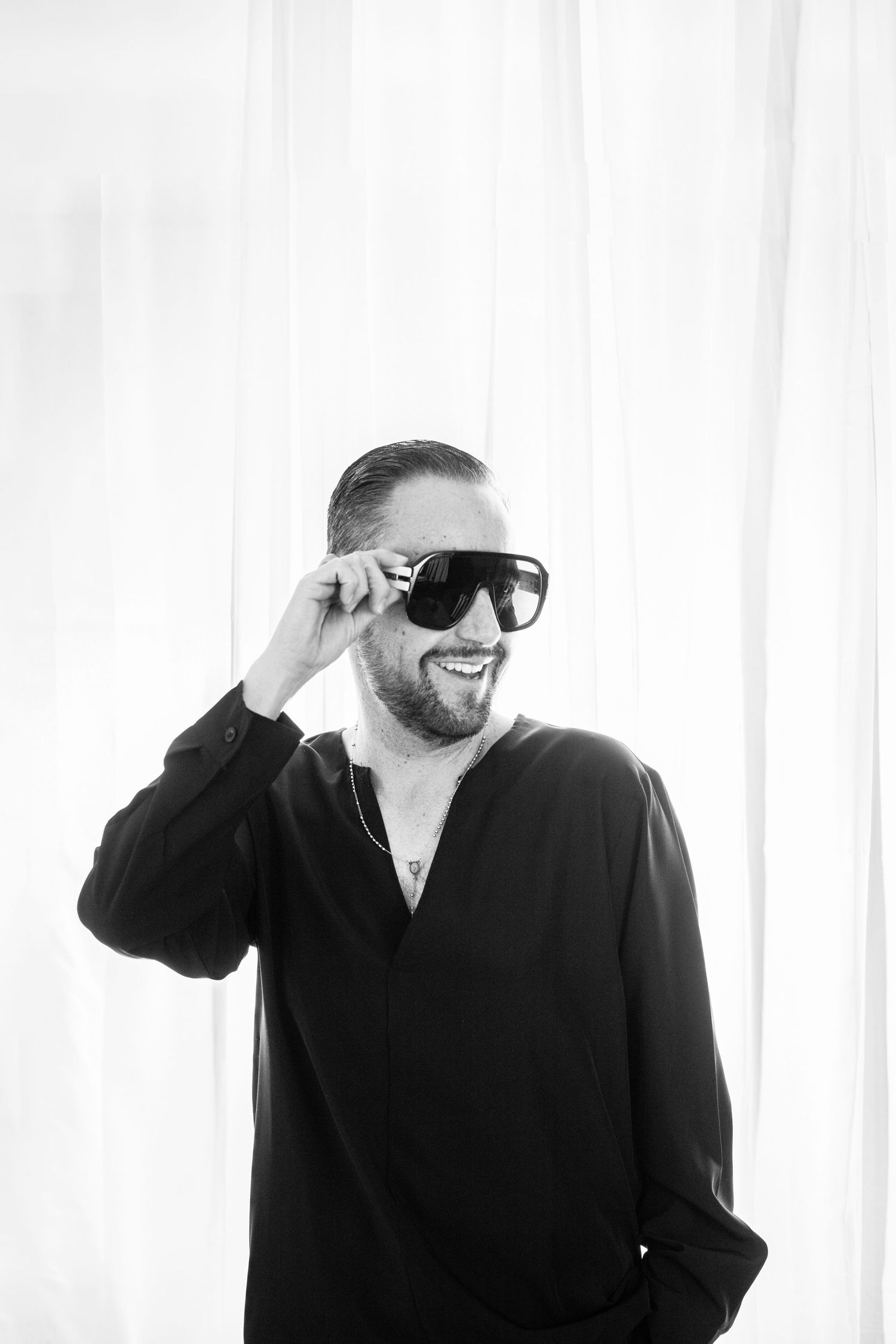 Three black and white photos of someone in a black shirt and sunglasses against a white background.