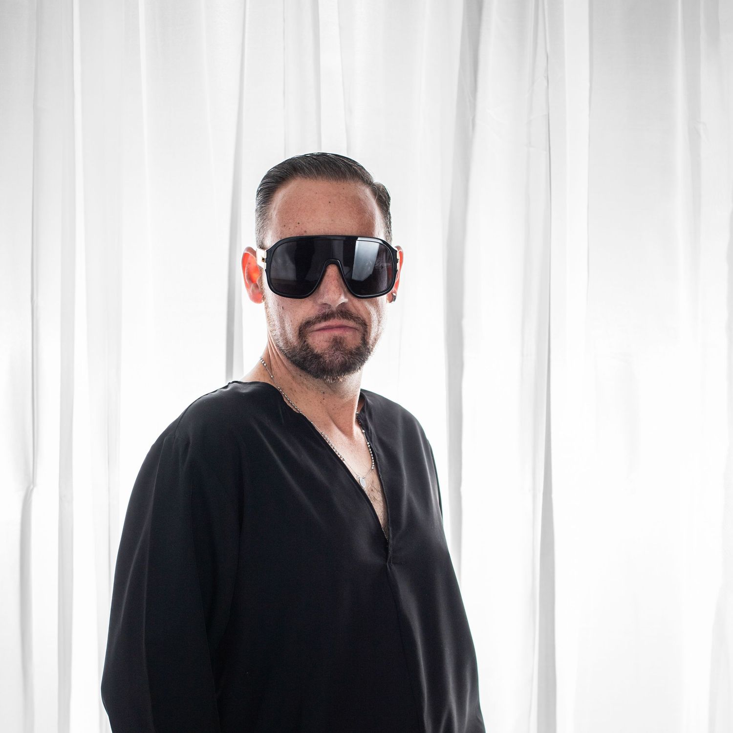 Artistic black and white photo sequence showing someone in dark clothing against a white curtained backdrop.