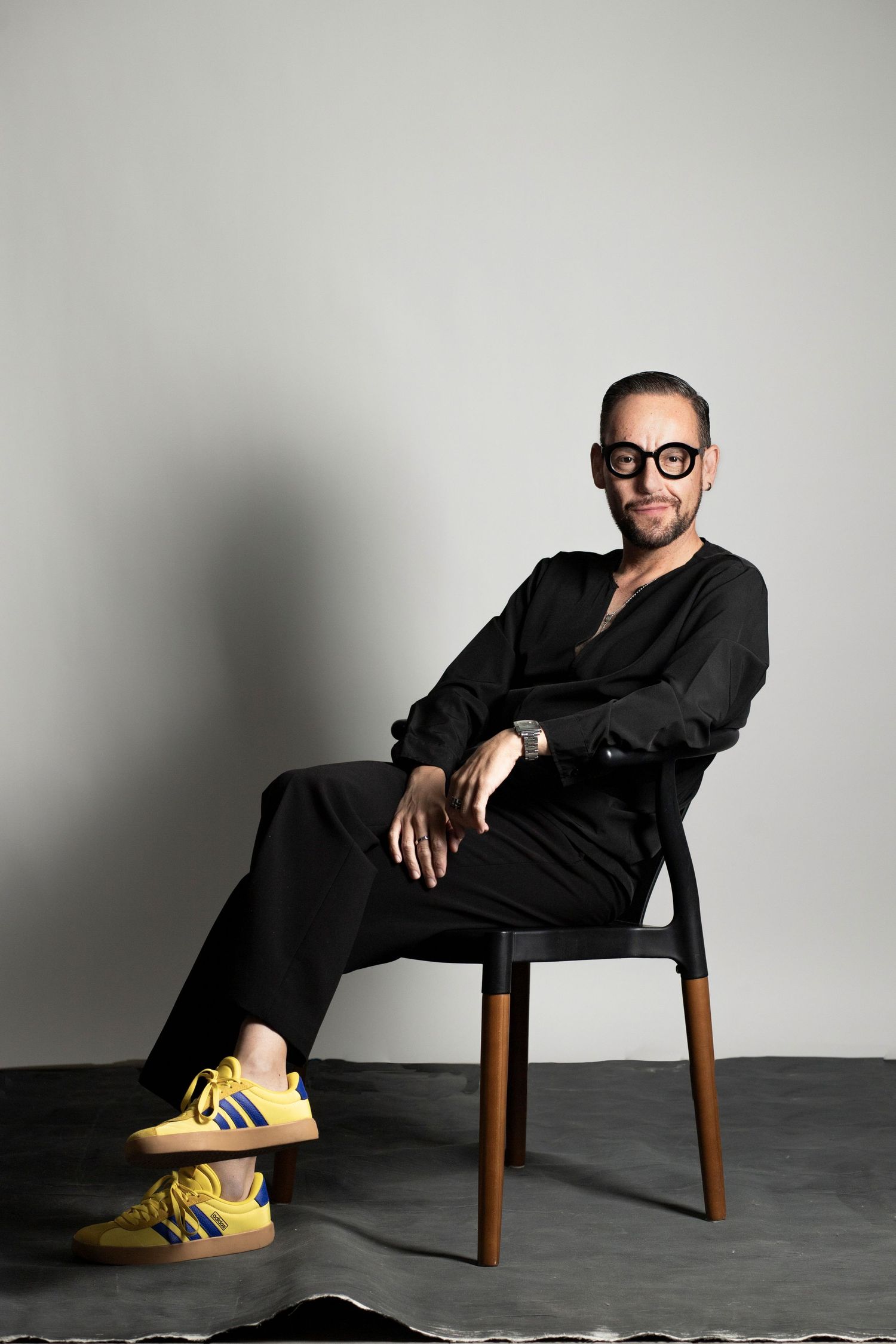 Artistic portrait series featuring a person in black attire with yellow shoes lounging in a wooden chair.