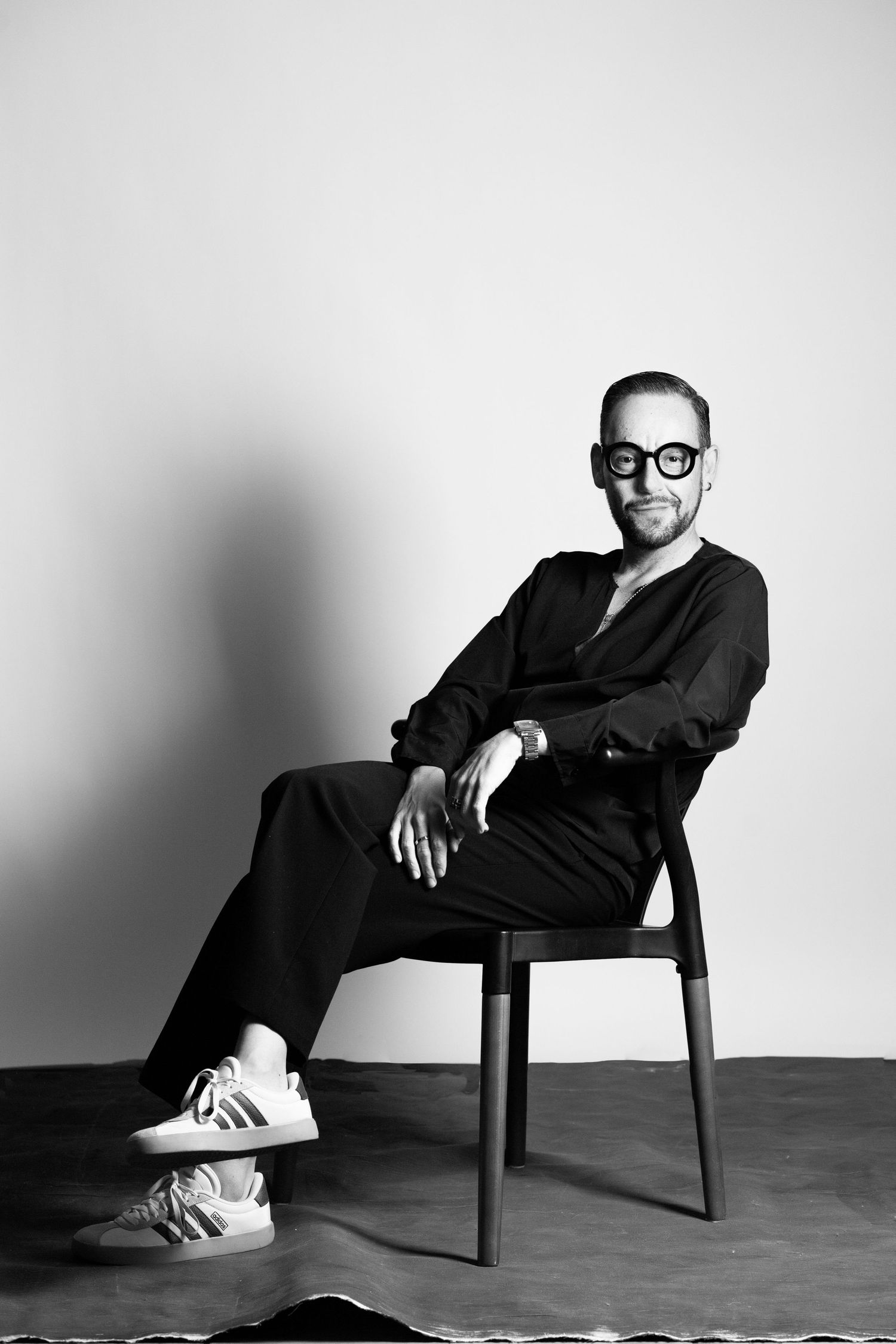 Artistic black and white photo series featuring someone in business attire seated in various relaxed poses on a chair.