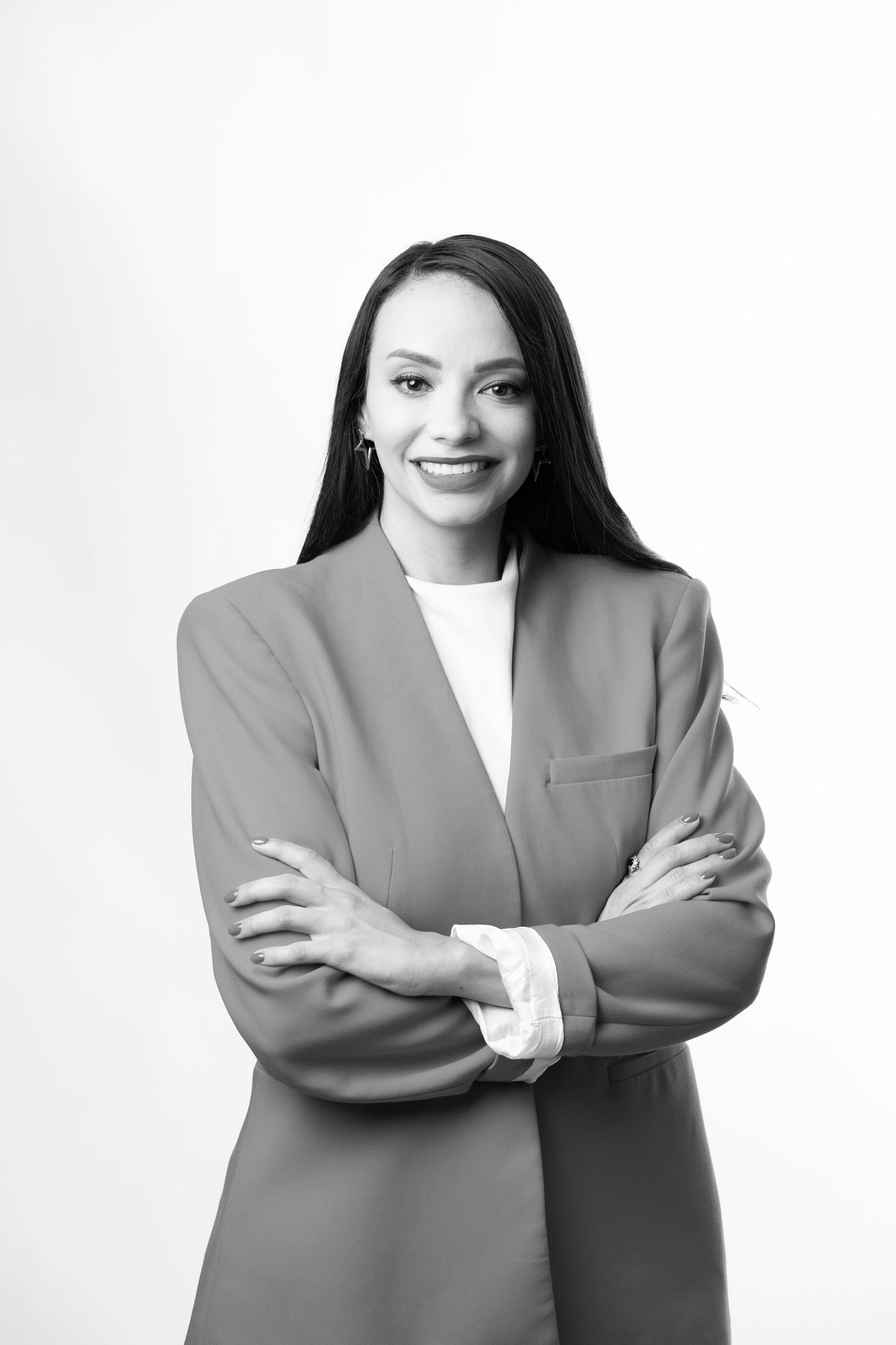 Professional black and white portrait of a confident businesswoman in a blazer with arms crossed and warm smile.