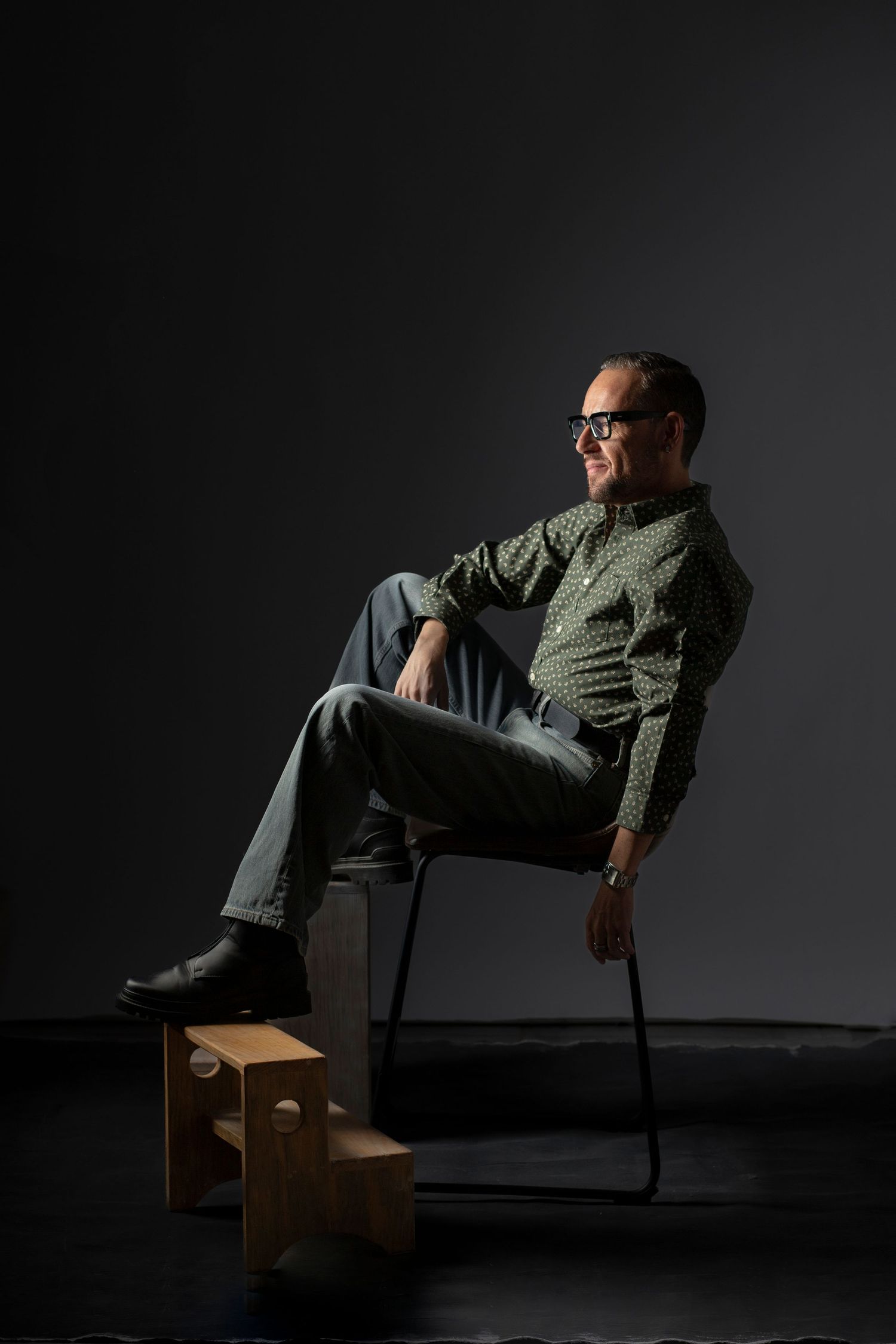 A dramatic series of four photos showing someone seated in a chair against a dark background with moody lighting.