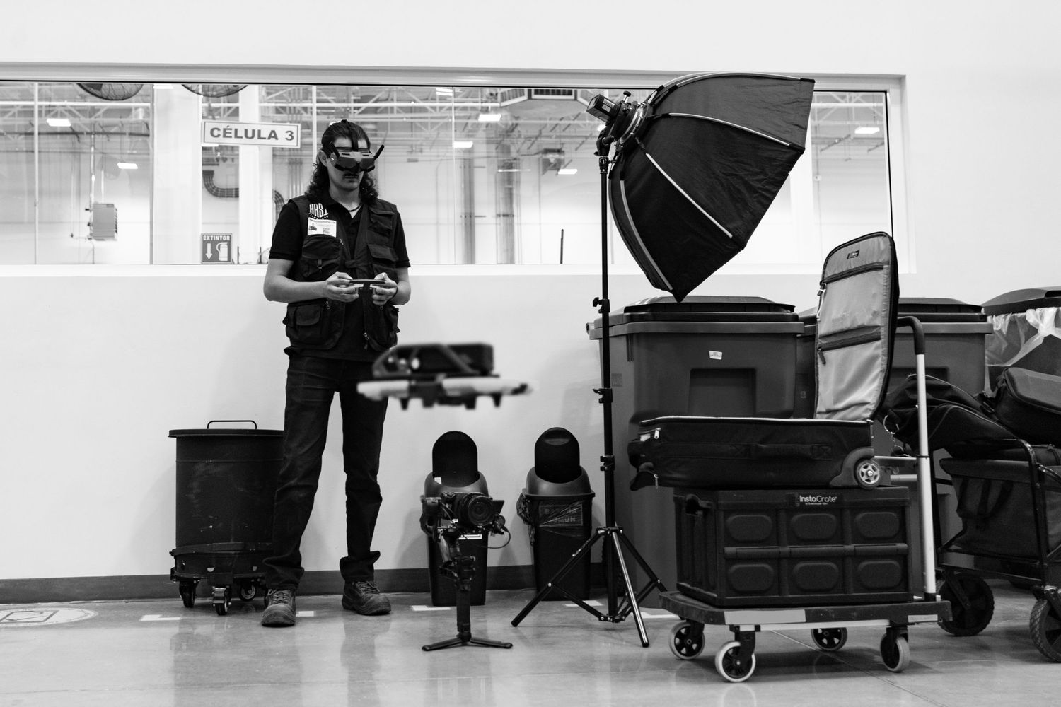 A photographer stands with professional lighting and camera equipment in a studio setting during a black and white photoshoot.