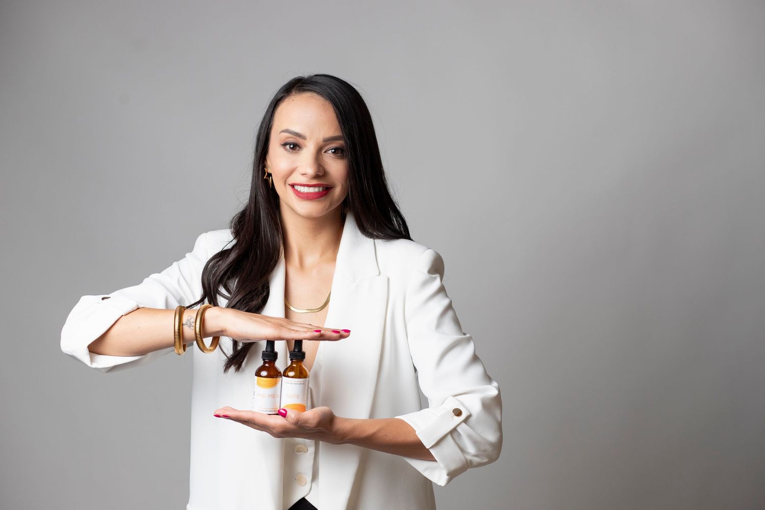 Professional in white blazer gestures and poses against gray background in dynamic business portrait series.