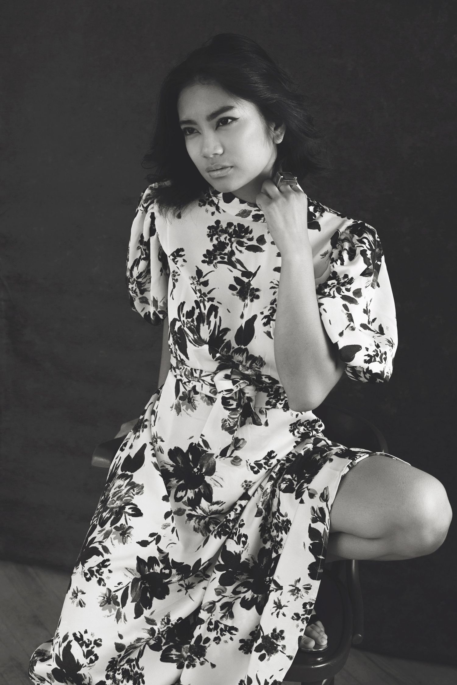 Black and white artistic portrait series showing person in floral print dress against dark background.