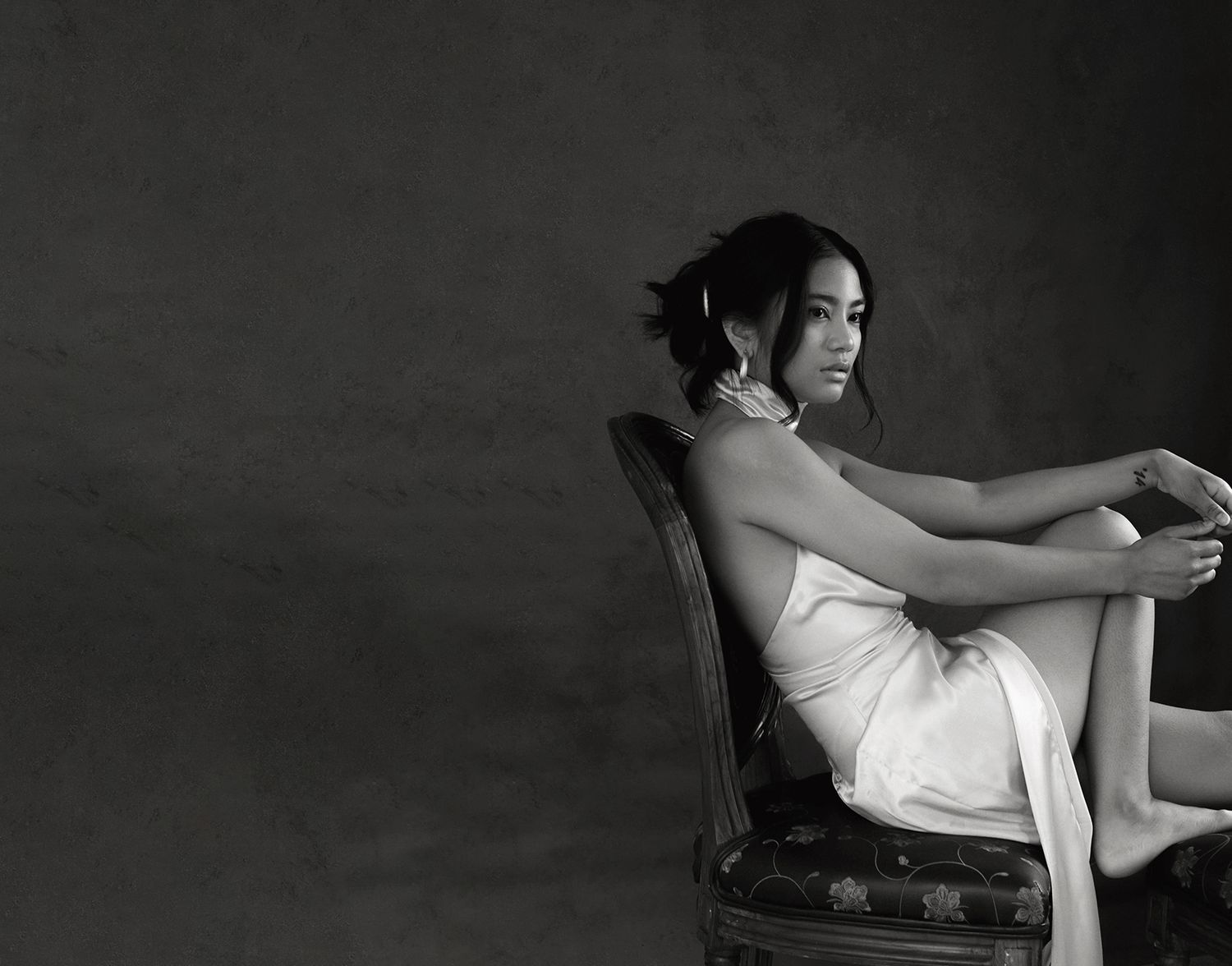 A dramatic black and white photo series showing a person in elegant poses against a dark background.