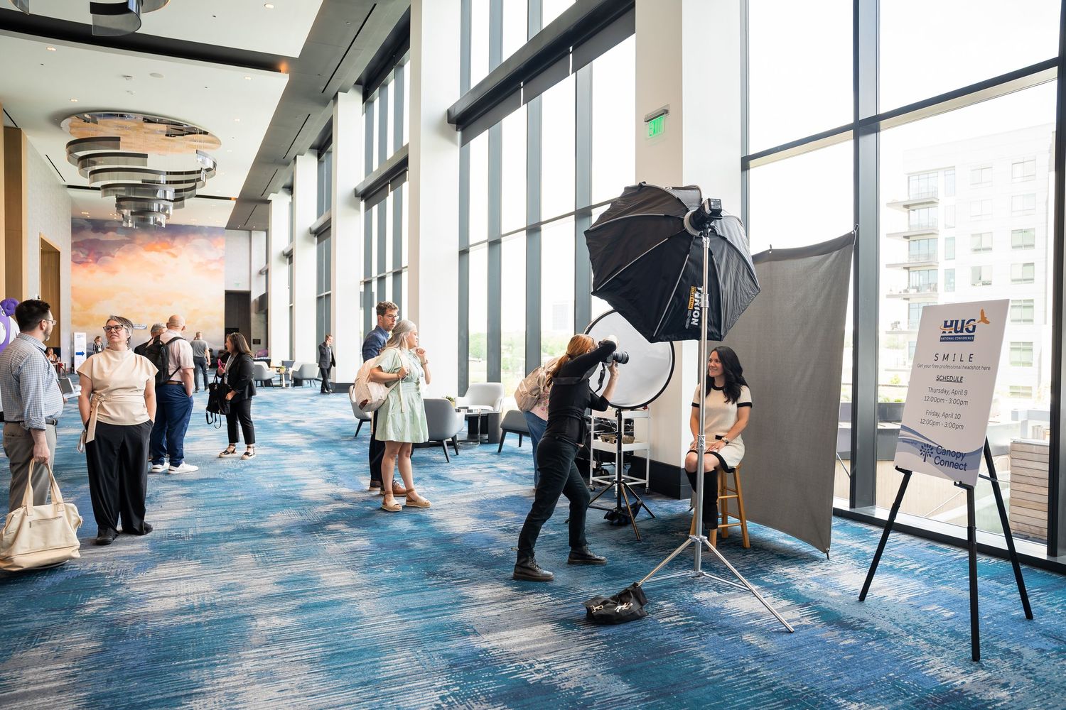 Conference attendees getting professional headshots taken in a bright modern convention center.