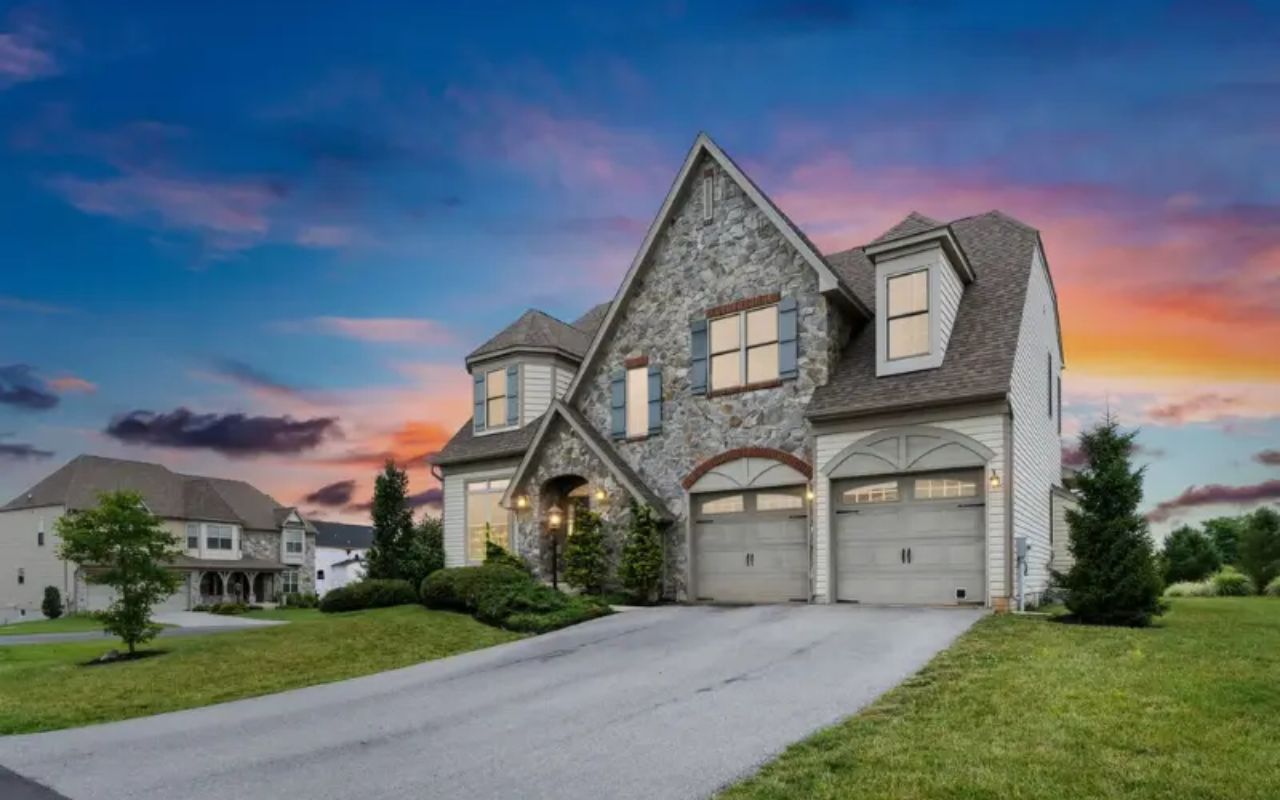 Exterior views of modern suburban homes with stone facades and attached garages at sunset.