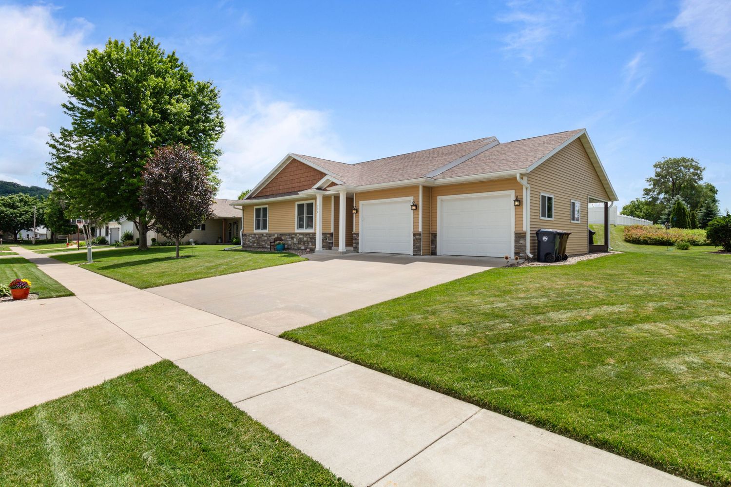 On-the-ground photo of house exterior, showcasing front view with landscaping and clear blue sky