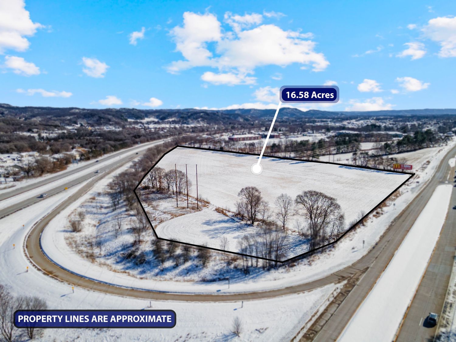 Aerial view of snow-covered property with curved road intersection and approximate 18.69 acre boundary lines marked.