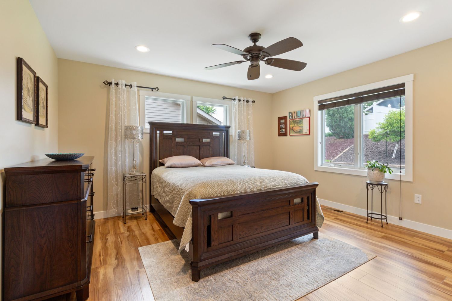 Interior photo of primary bedroom with abundant natural light, windows, and elegant wood floors